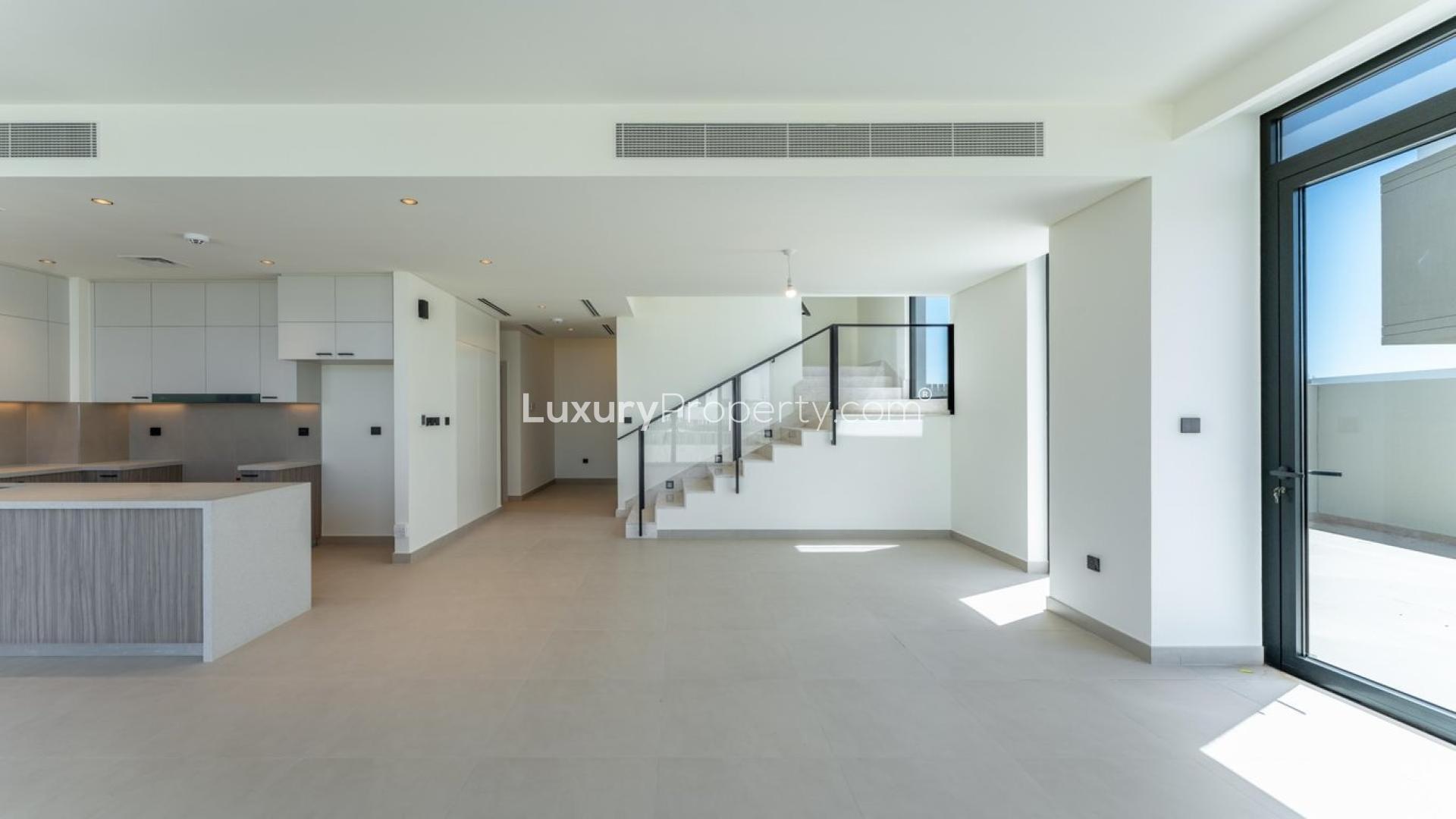 "Open-plan living area in Golf Grove villa, Dubai Hills Estate, with modern kitchen and staircase.",Modern open-plan living area in Dubai Hills Estate villa, featuring sleek kitchen and staircase