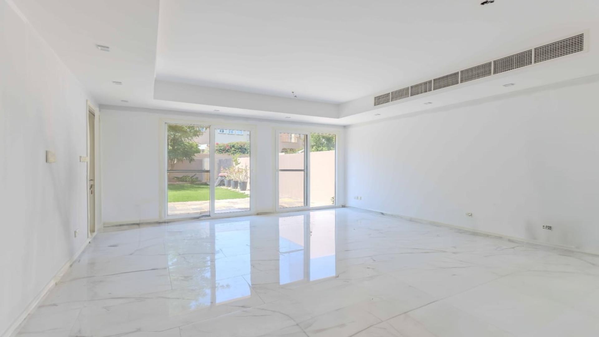 "Spacious villa garden with lush greenery in Springs 11 community, ideal for serene family living.",Spacious living room in The Springs villa with large windows and garden view