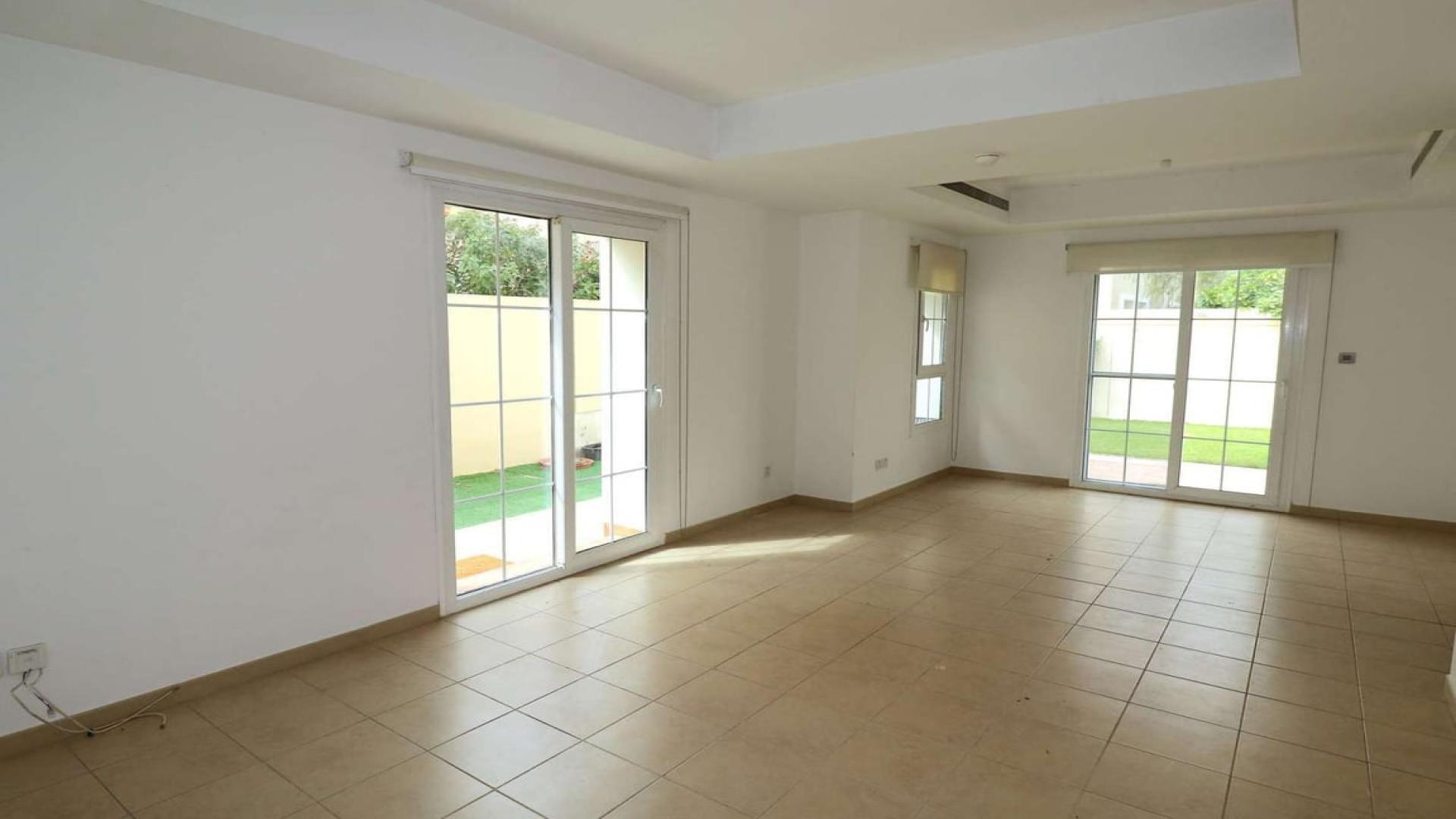 Bright living room with tiled floors and garden view in Al Reem villa, Arabian Ranches