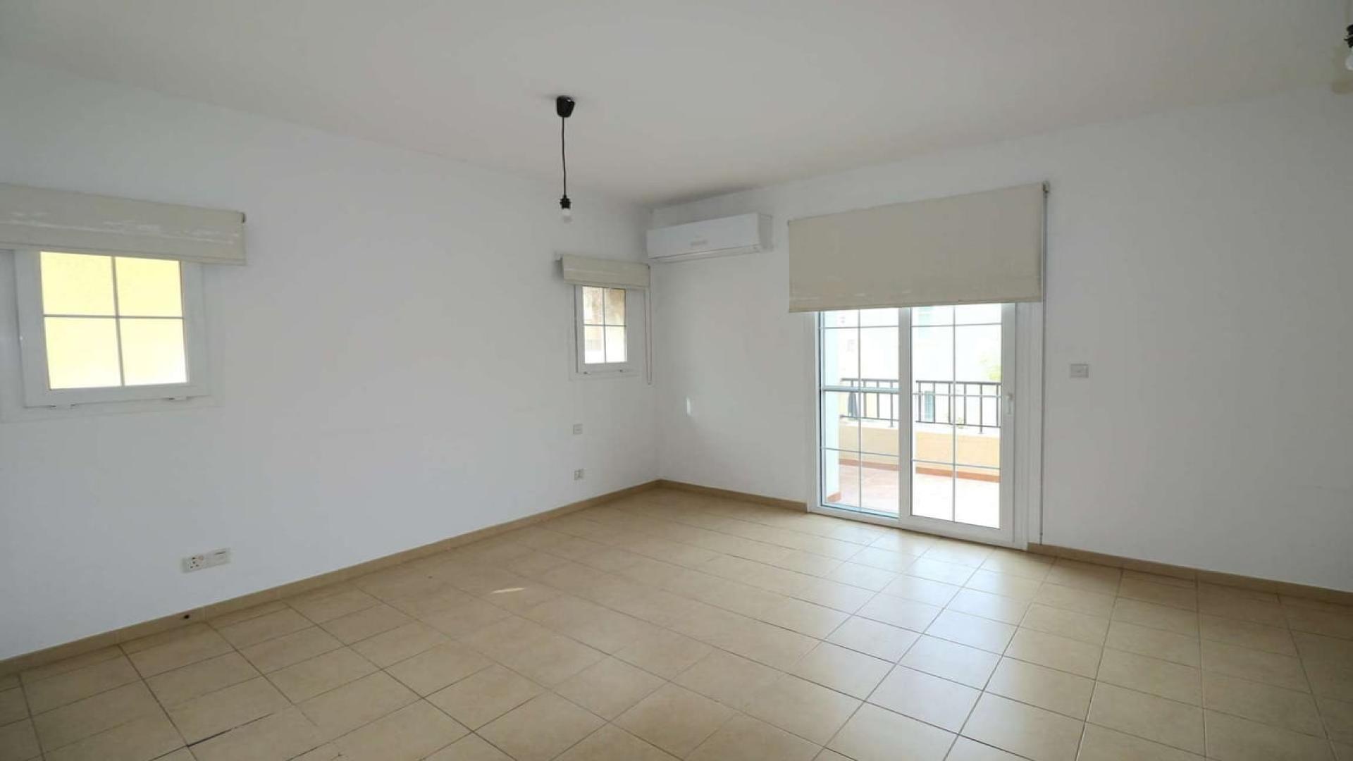 Alt text: "Elegant three-bedroom villa with garden in Al Reem, Arabian Ranches for sale.",Empty room with tiled floor and large windows in Al Reem villa, Arabian Ranches