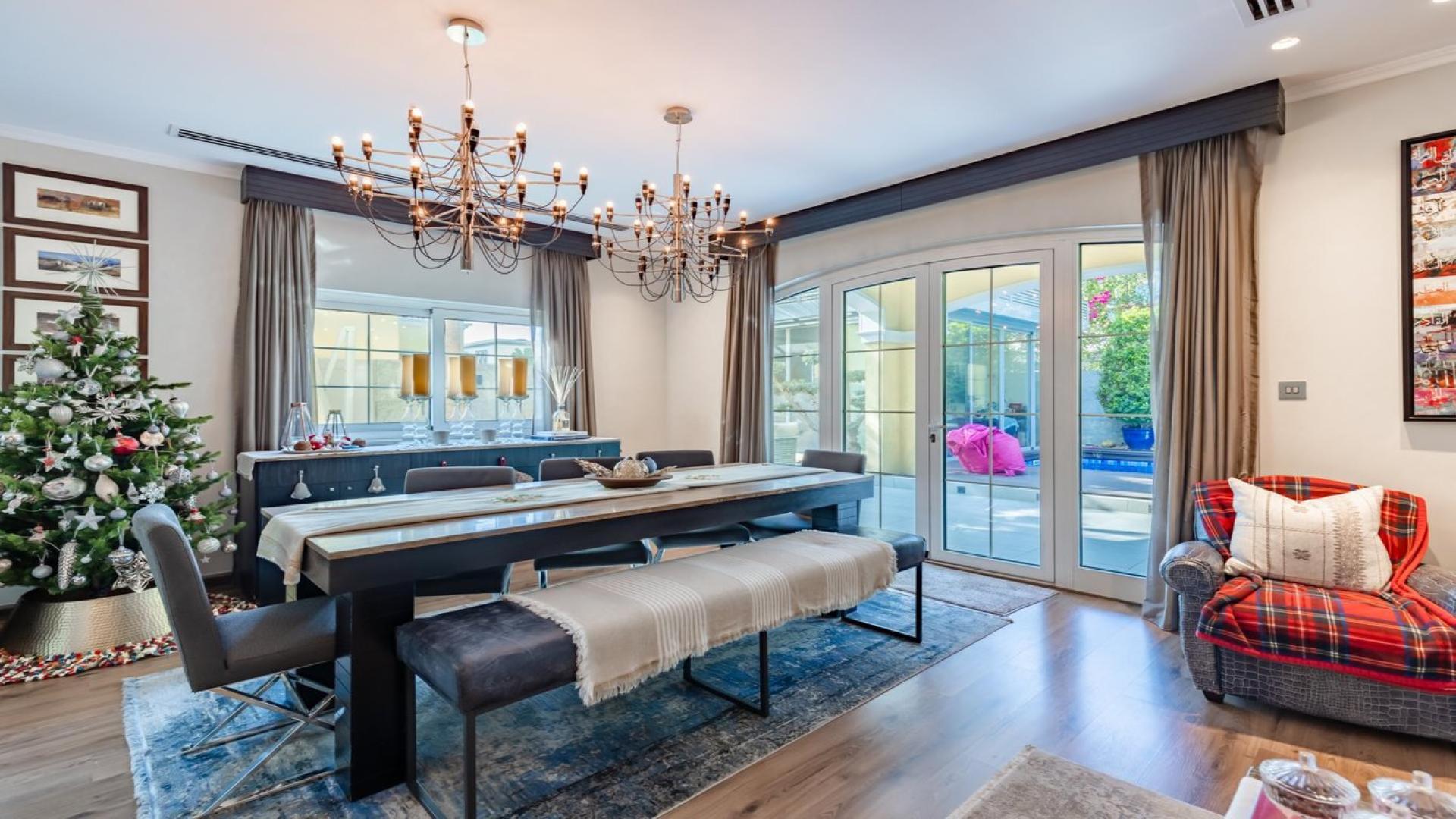 Dining room in upgraded Jumeirah Park villa, featuring elegant chandeliers and garden view