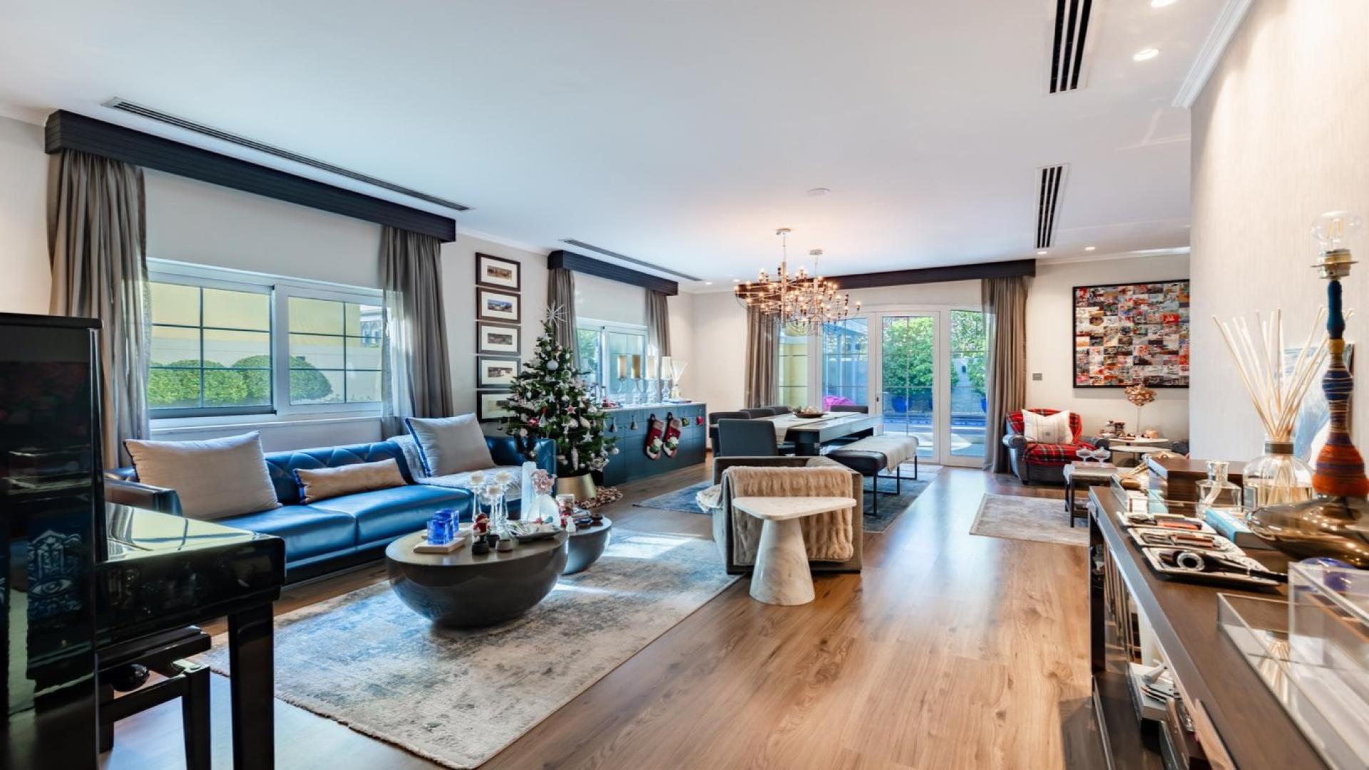 "Upgraded Jumeirah Park Legacy villa exterior with garage and lush greenery, for sale.",Luxurious living room in upgraded Jumeirah Park villa, featuring elegant decor and natural light