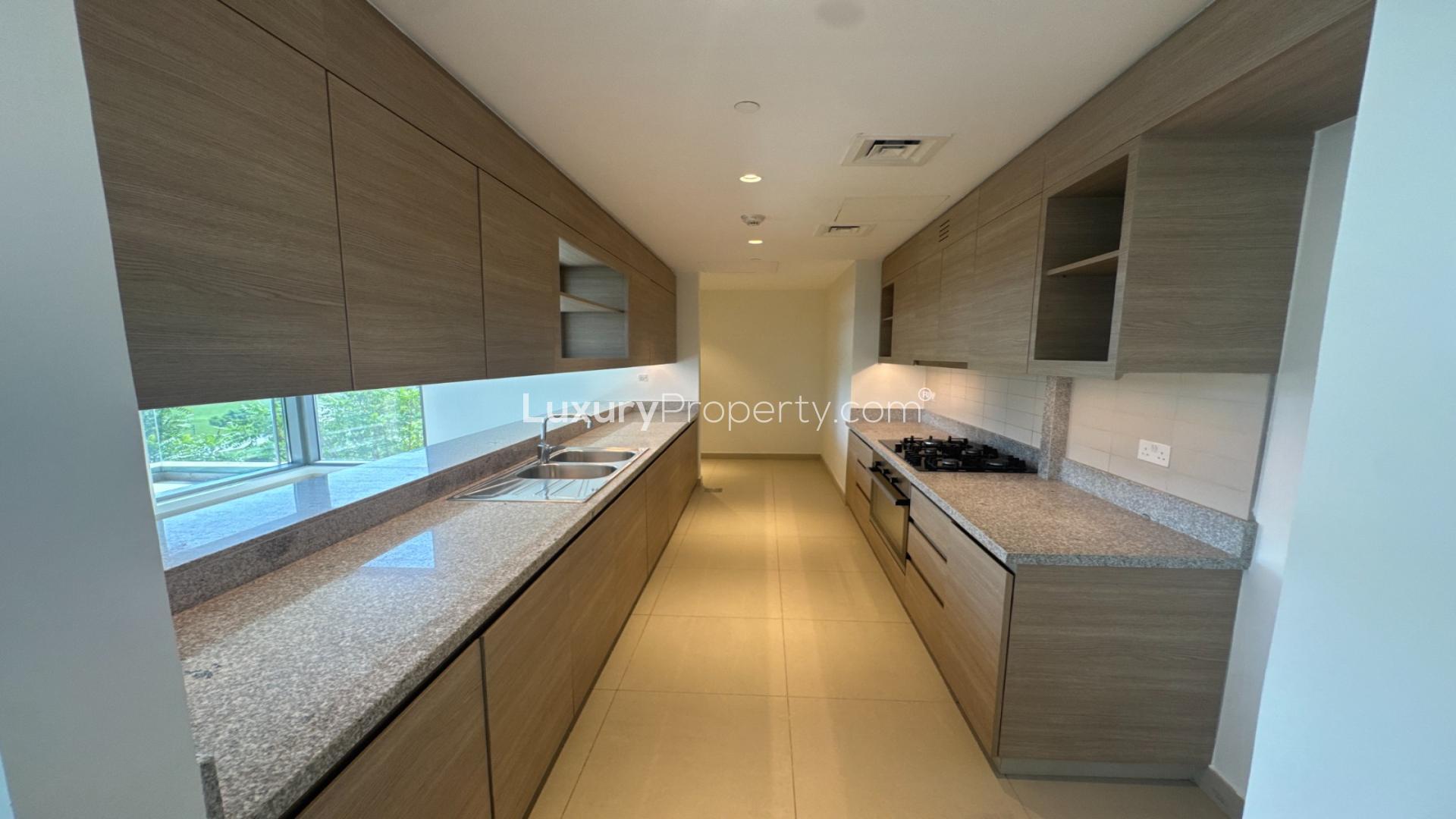 Modern kitchen in Dubai Hills Acacia apartment with granite countertops and ample cabinetry