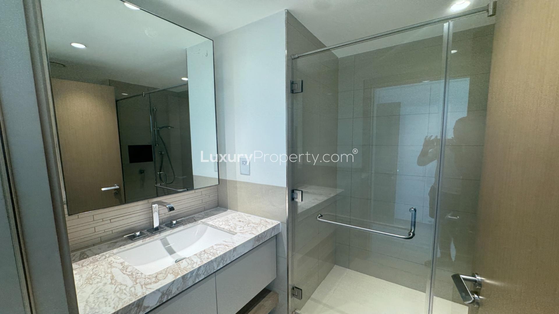 "Balcony view of lush greenery in Acacia B, Dubai Hills Estate apartment for rent.",Modern bathroom with glass shower in Acacia B apartment, Dubai Hills Estate for rent
