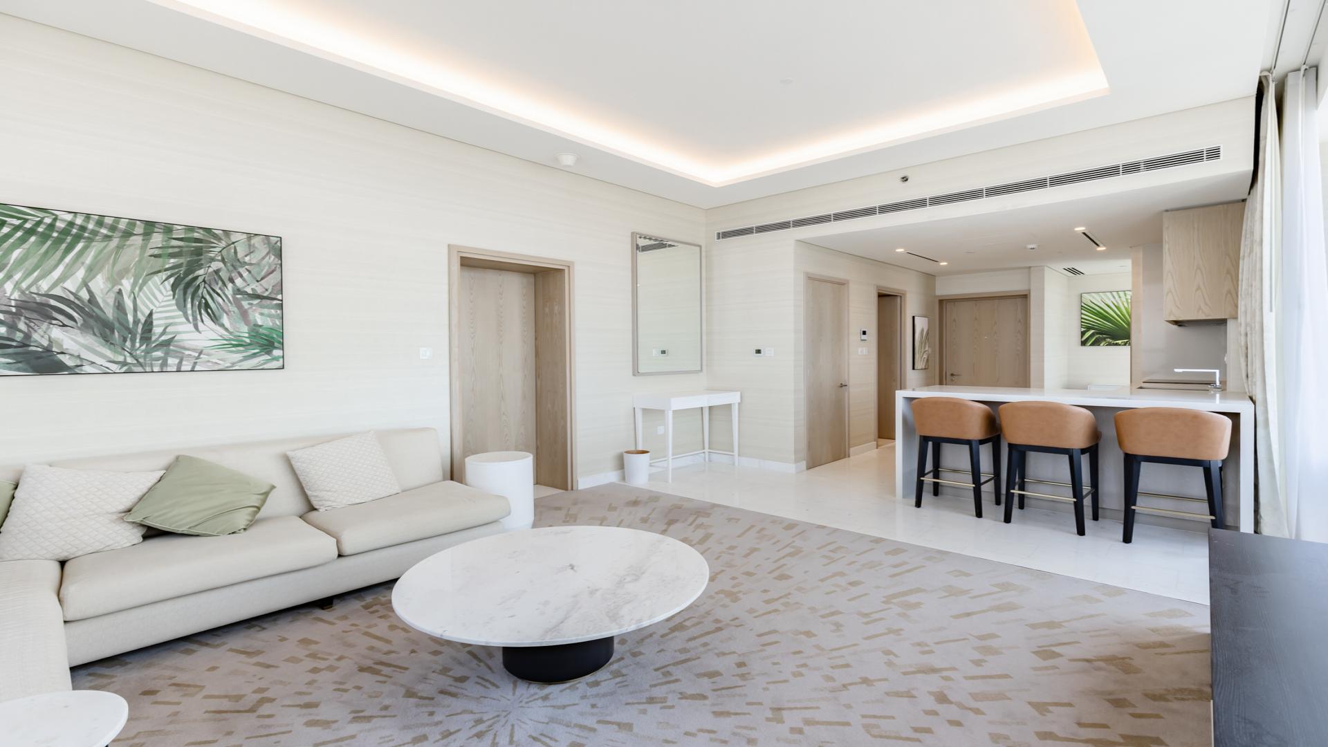 Modern living room in Palm Jumeirah apartment, featuring elegant decor and open kitchen area