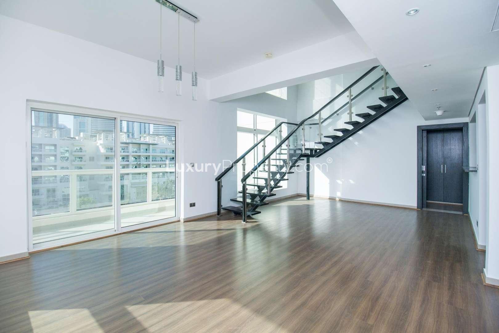 Open-plan living area in Jumeirah Heights duplex apartment with modern staircase and hardwood flooring