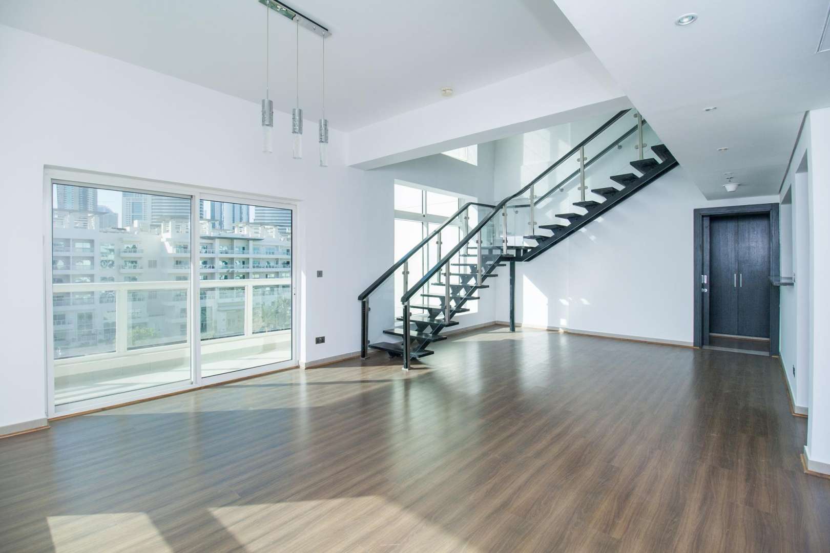 Open-plan living area in Jumeirah Heights duplex apartment with modern staircase and hardwood flooring