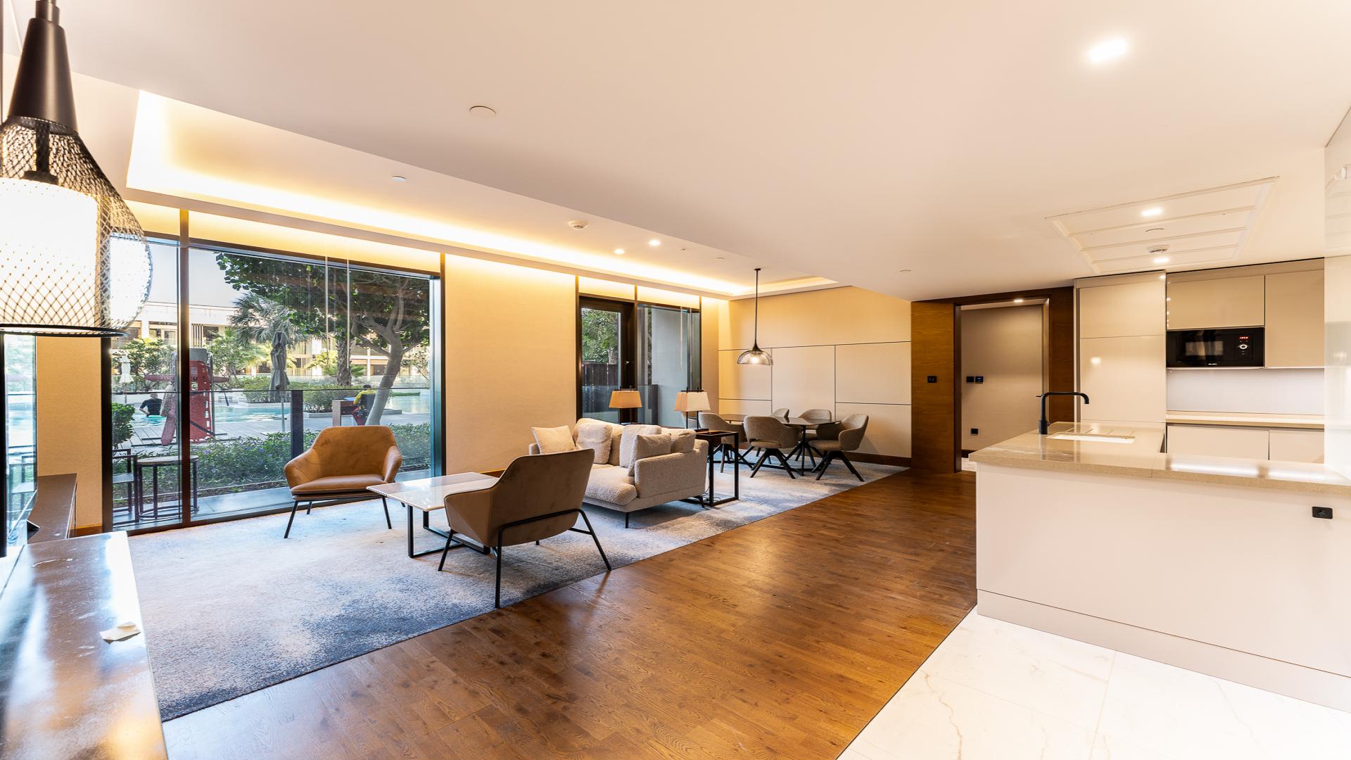 Modern furnished living area in Bluewaters Residences apartment, featuring open kitchen and pool view