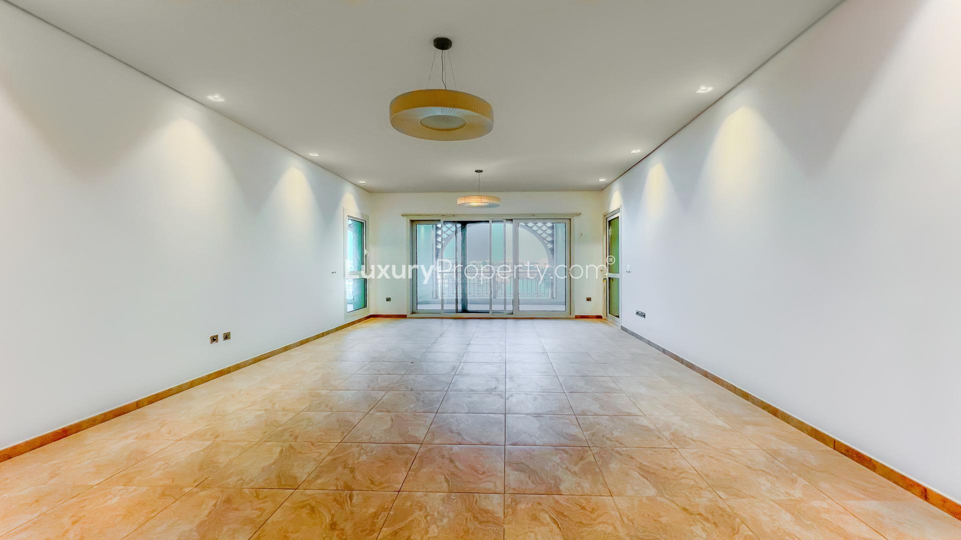 Spacious living area in Palm Jumeirah apartment with marina views, tiled floors, and large windows