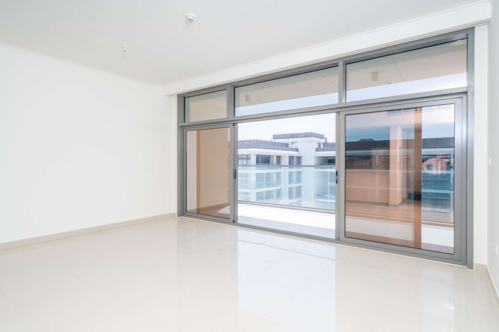 "Modern apartment building with pool in Dubai Hills Estate's Park Heights community.",Empty living room with large windows in Dubai Hills Estate apartment for rent