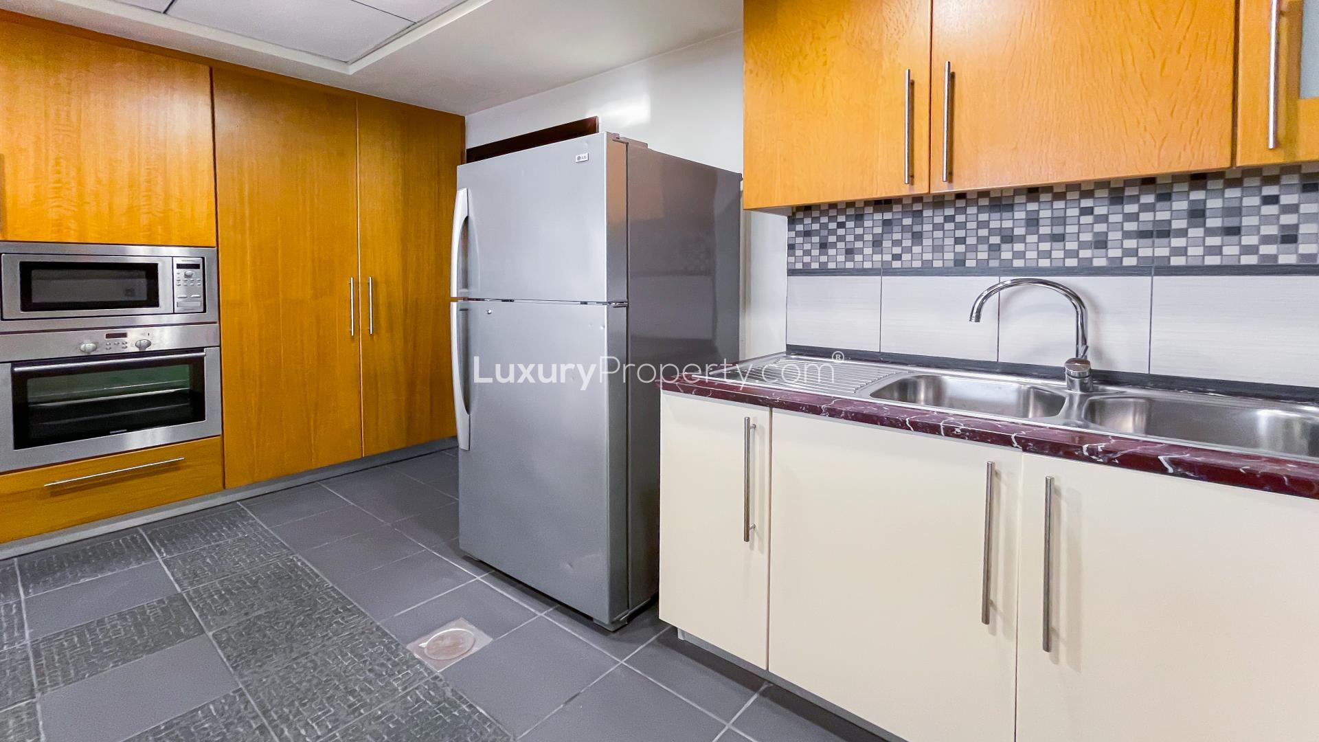 Modern kitchen in spacious JBR apartment, Murjan, with marble countertops and wooden cabinets