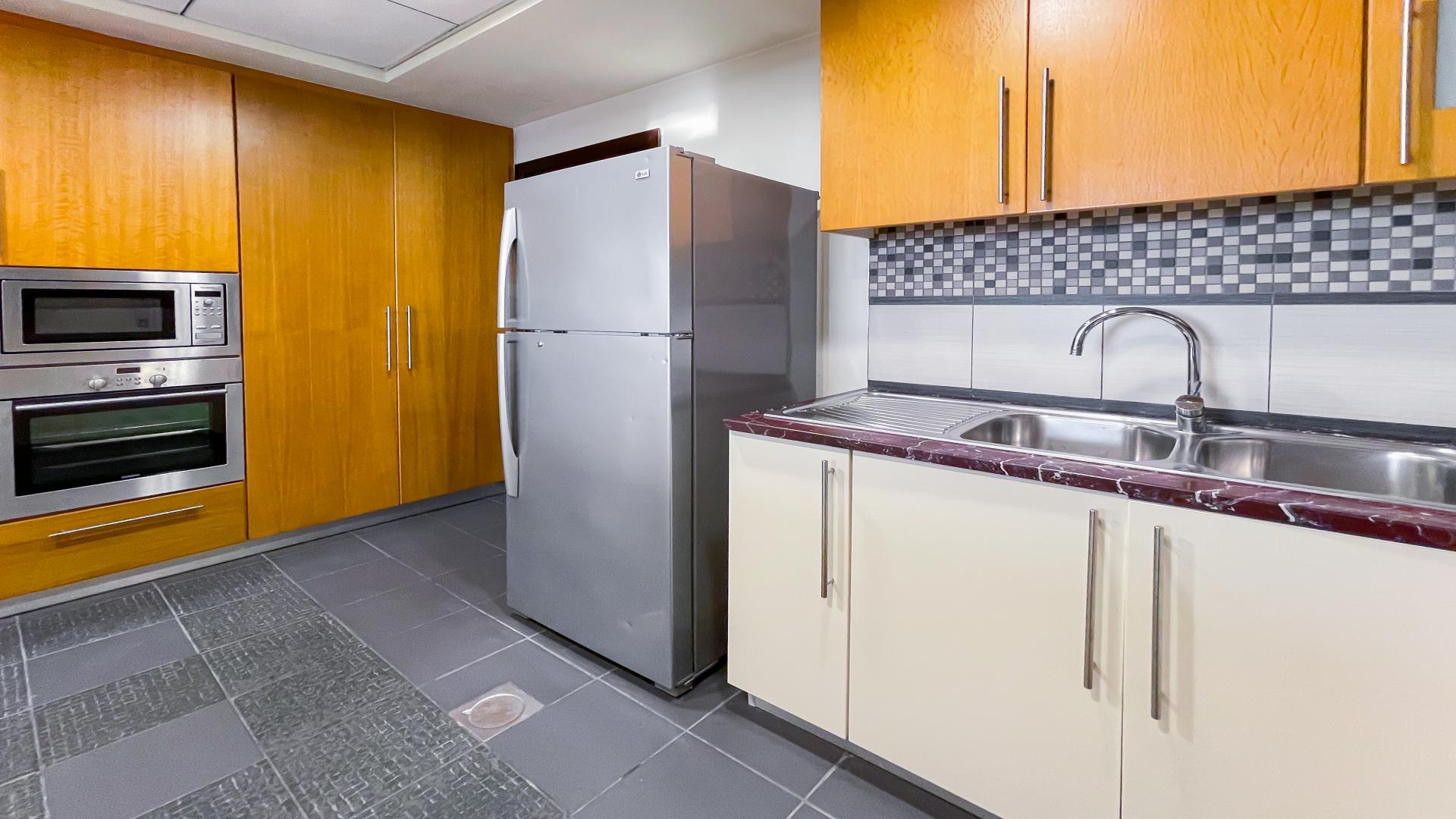 Modern kitchen in spacious JBR apartment, Murjan, with marble countertops and wooden cabinets