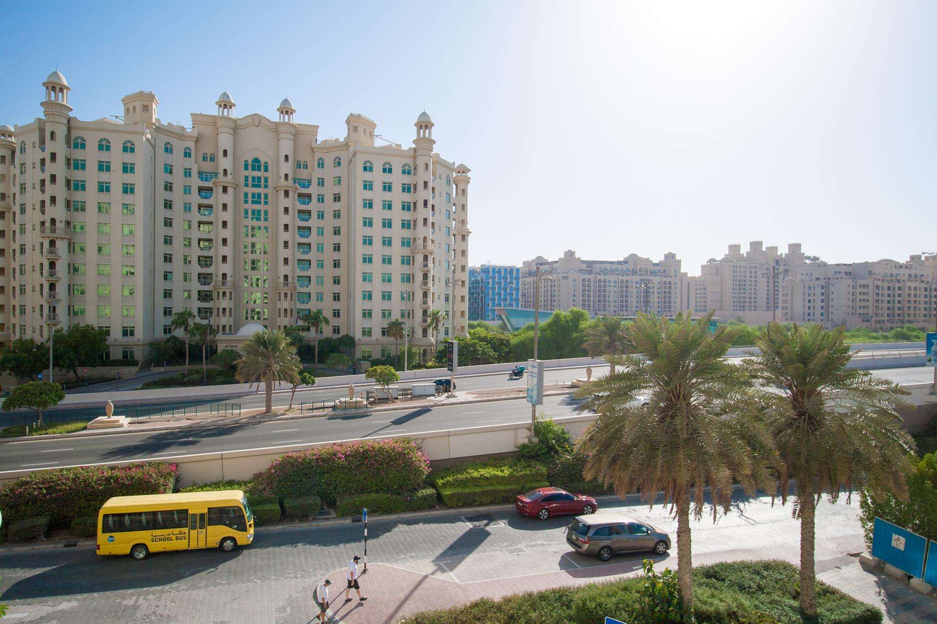 Exterior view of Shoreline Residences, Palm Jumeirah, featuring lush greenery and road