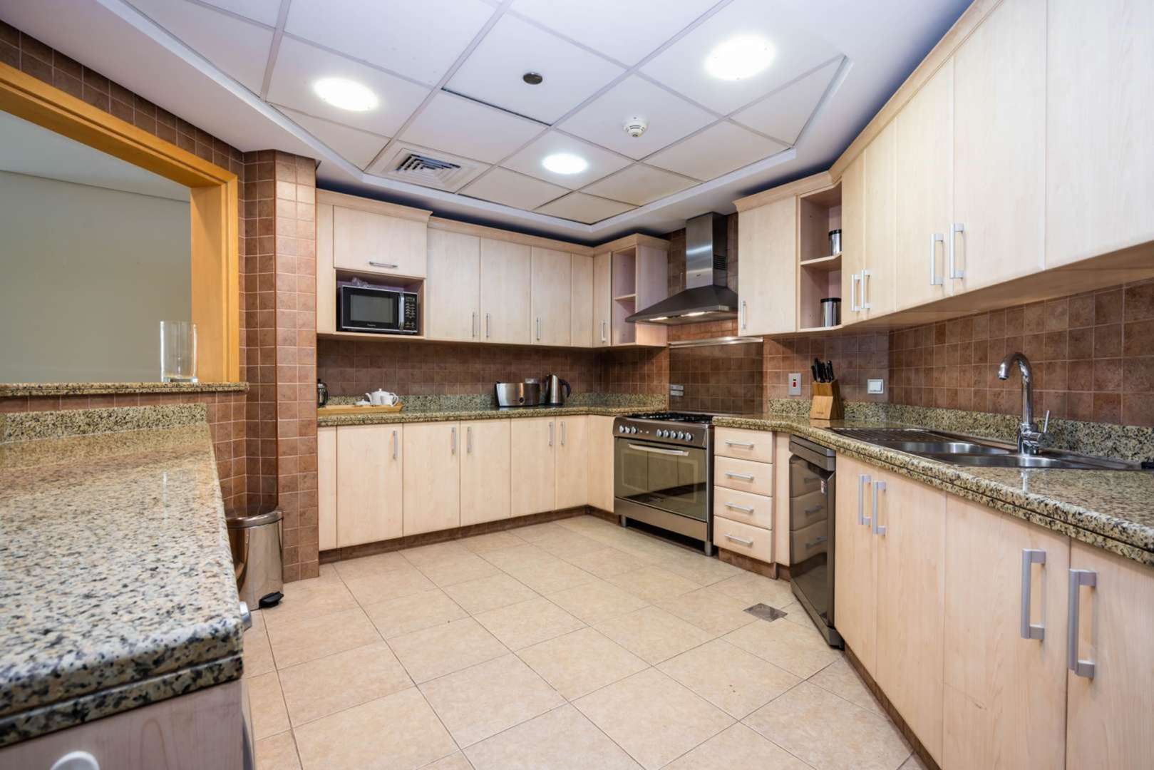 "Exterior view of Shoreline Residences apartment with lush palm trees in Palm Jumeirah.",Modern kitchen in spacious Shoreline Residences apartment, Palm Jumeirah, with granite countertops