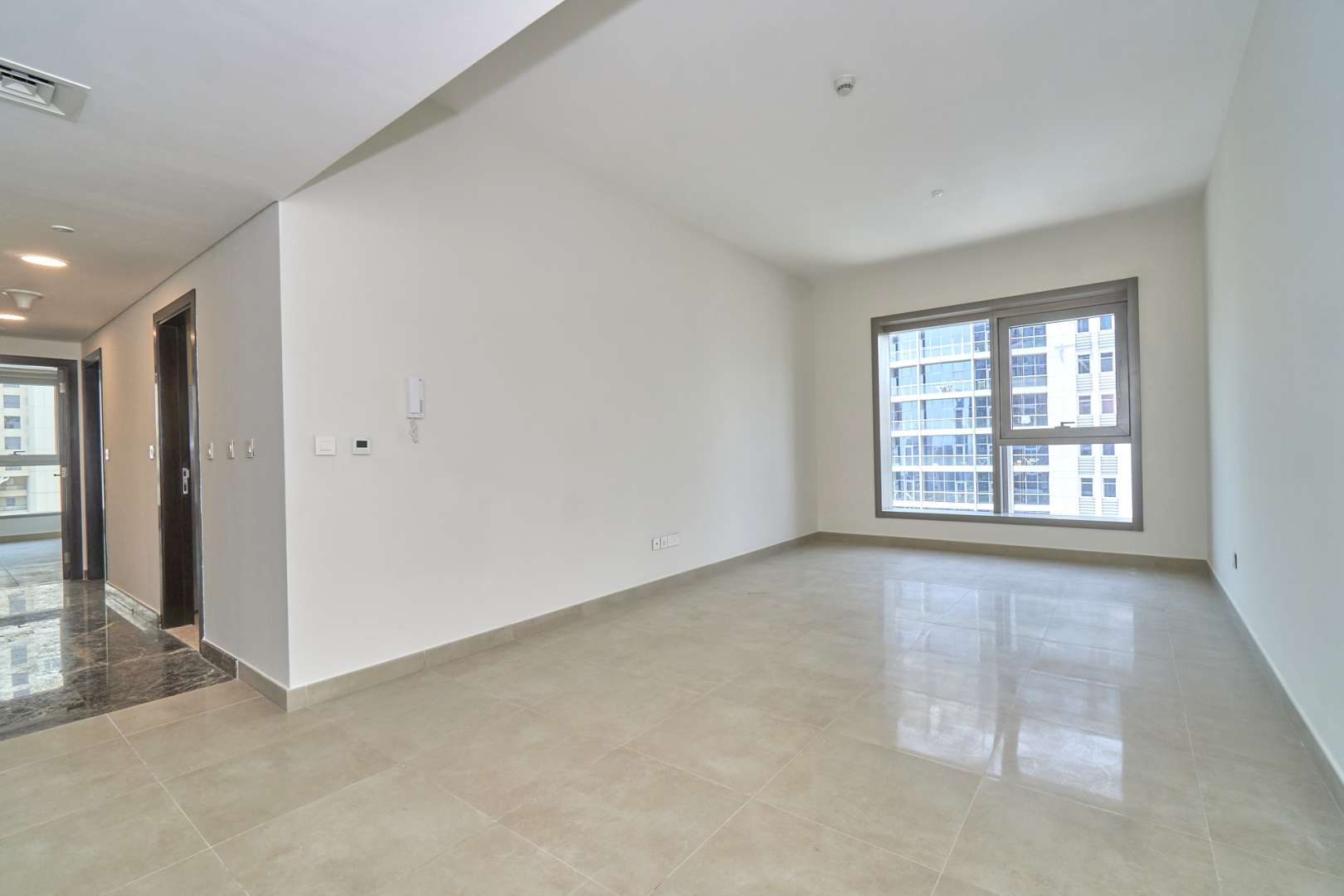 Empty living room in 3-bedroom Dubai Marina apartment, large window, tiled floor