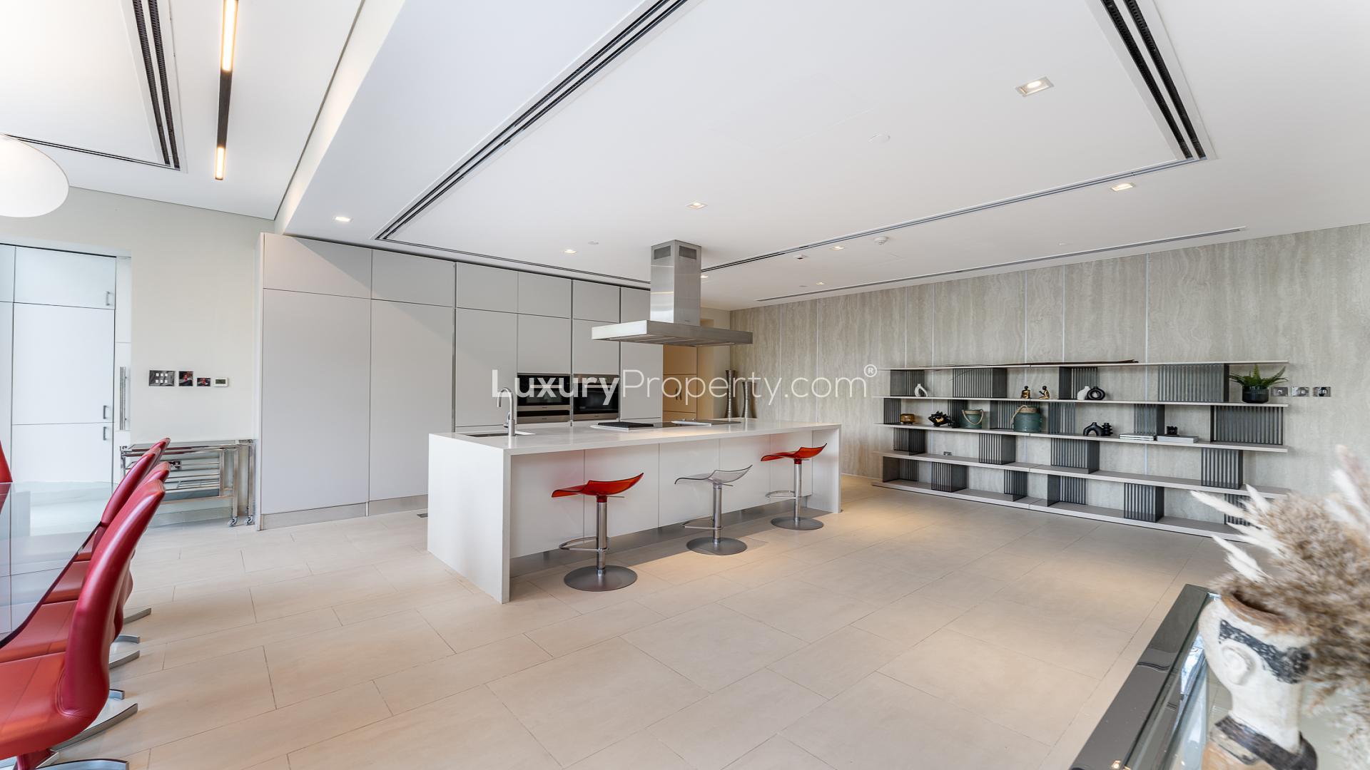 Modern kitchen in 3-bedroom duplex, Seventh Heaven, Al Barari with sleek design and red chairs