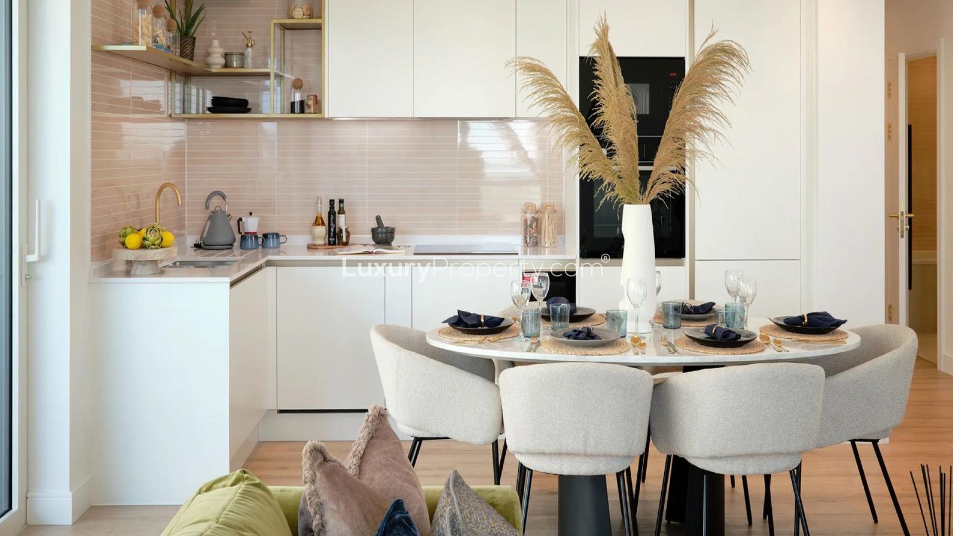 Modern kitchen with blue cabinets and dining area in Waterview House apartment, Wemble