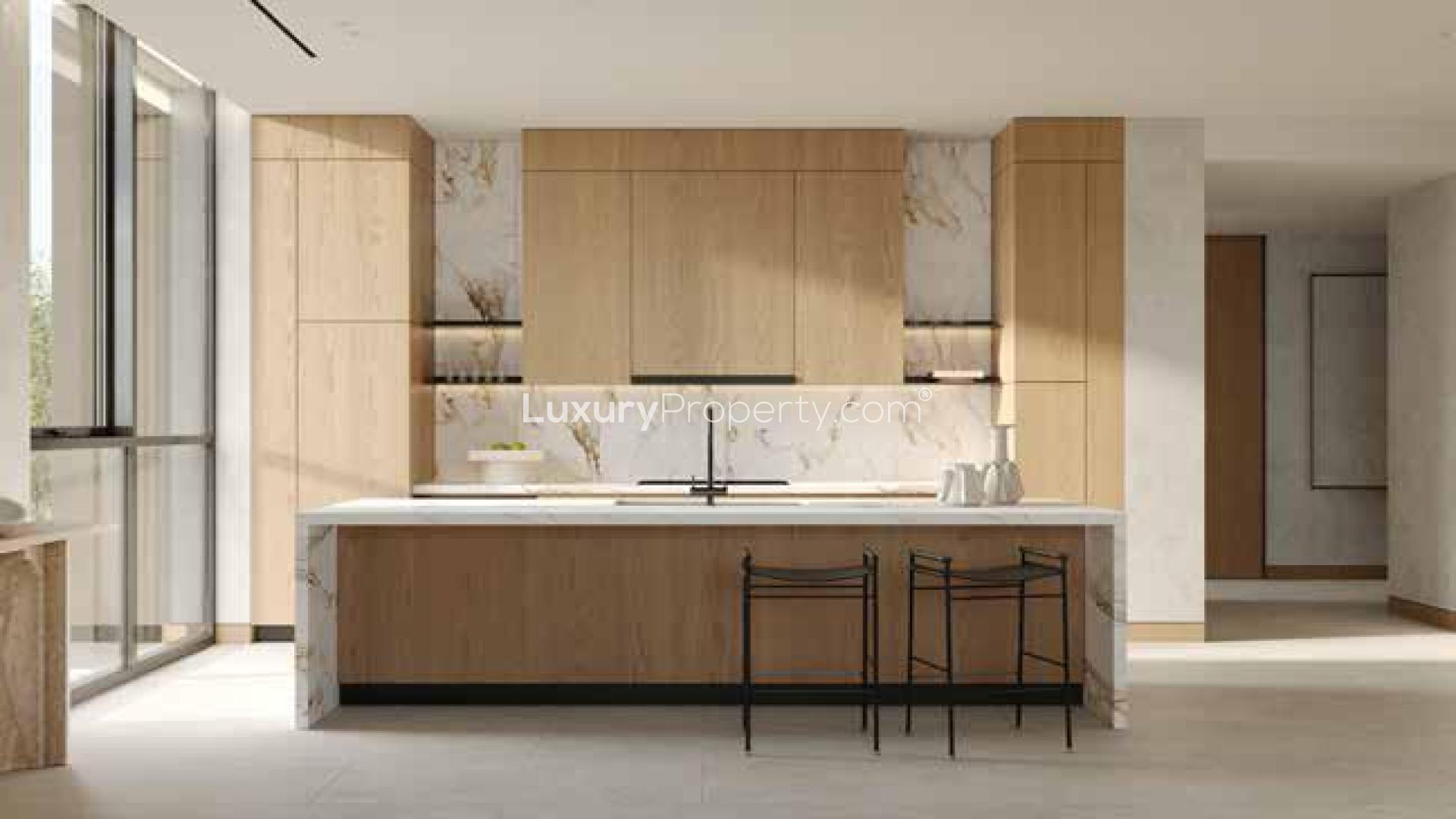 Modern kitchen and dining area in Al Barari apartment, featuring wooden cabinetry and natural light