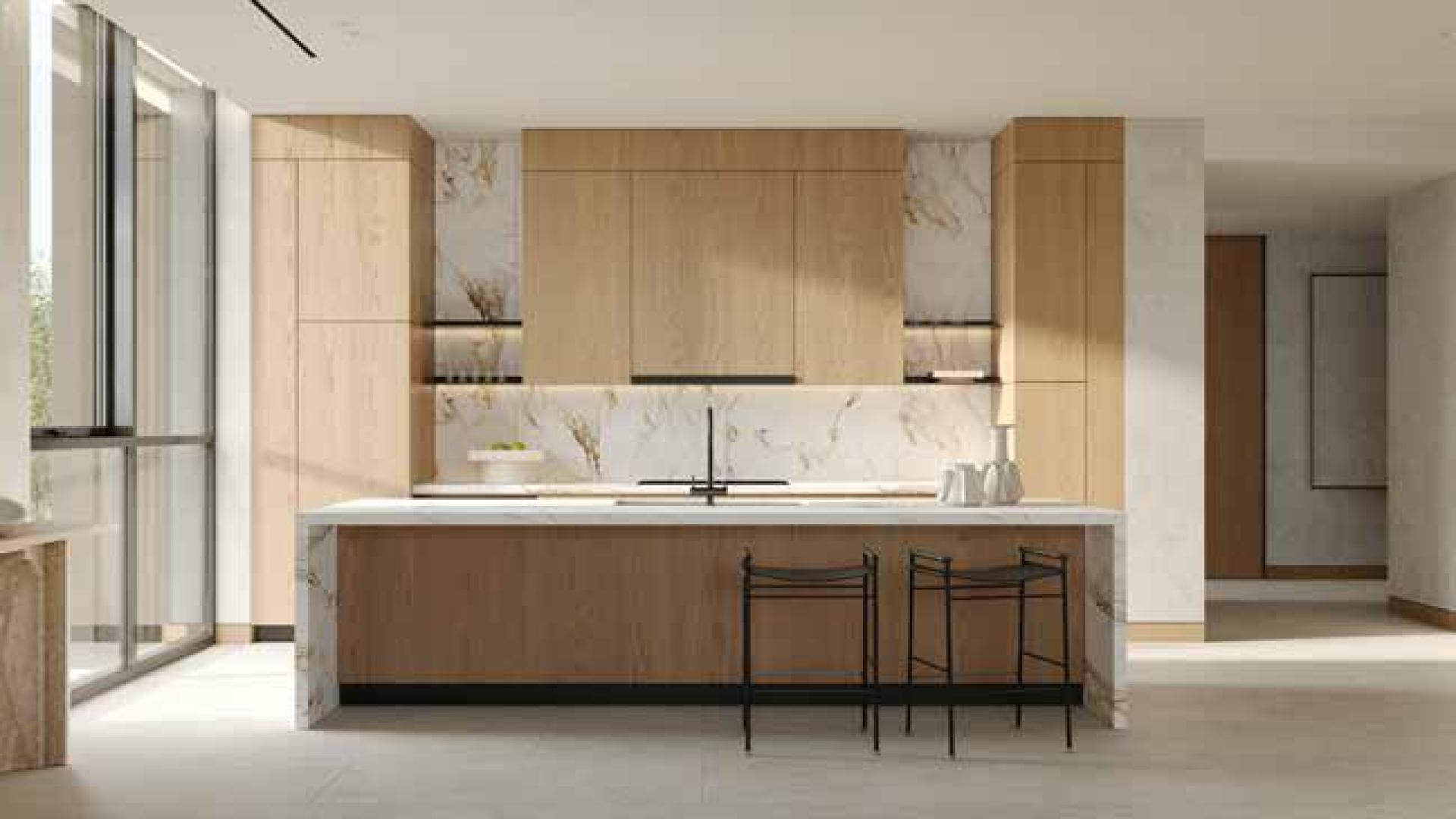 Modern kitchen and dining area in Al Barari apartment, featuring wooden cabinetry and natural light