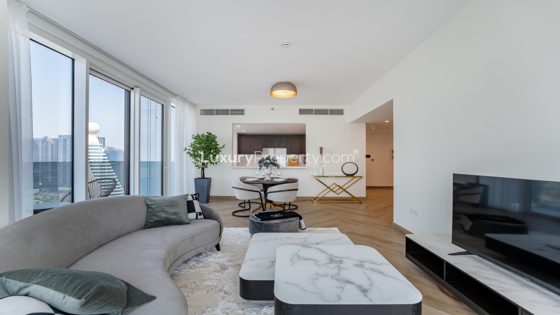 Modern living room in Al Kifaf apartment with skyline views, large windows, elegant decor