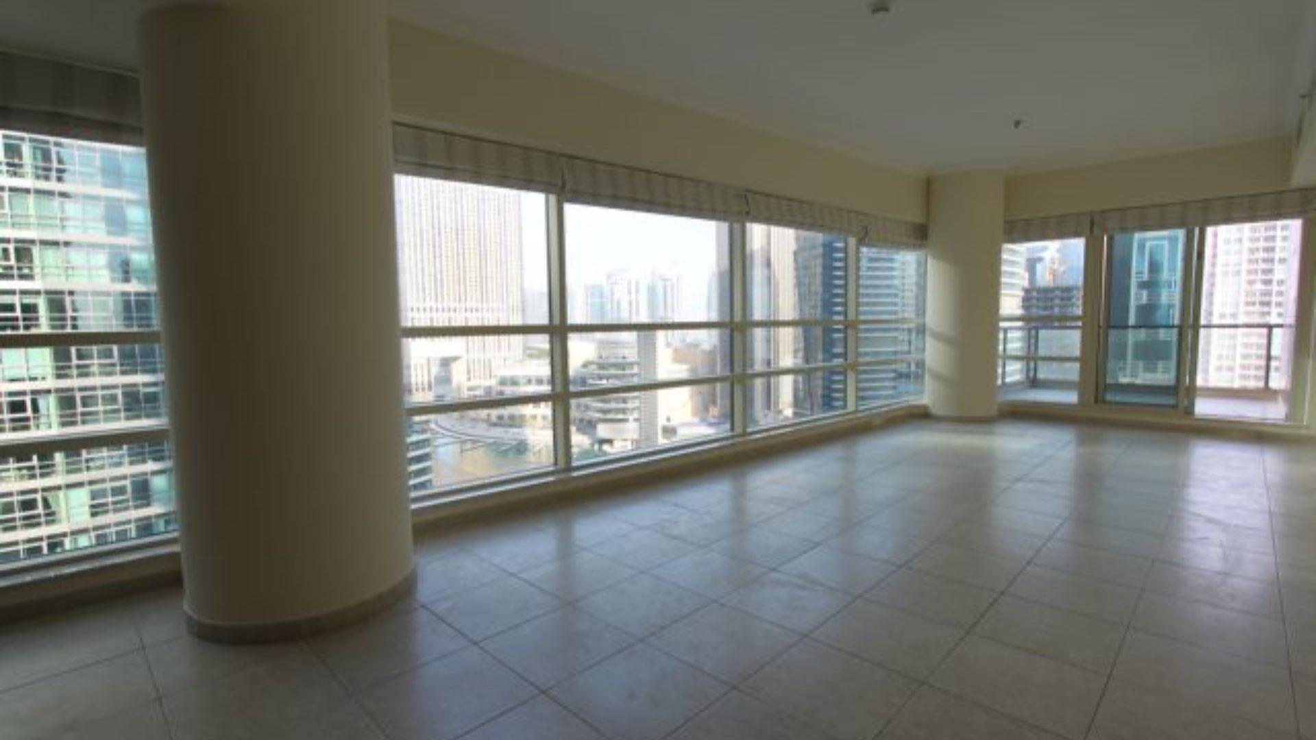 Spacious living room with large windows, overlooking Dubai Marina skyline in Al Sahab apartment