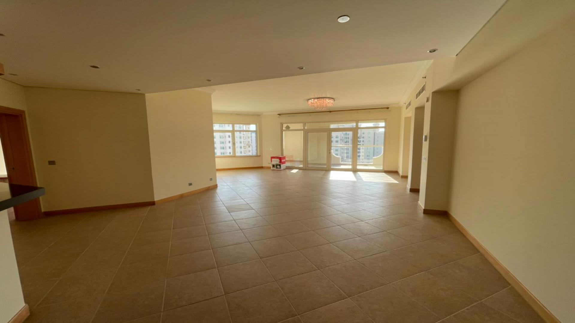 Empty room in Shoreline Apartments, Palm Jumeirah, with tiled floor and open door
