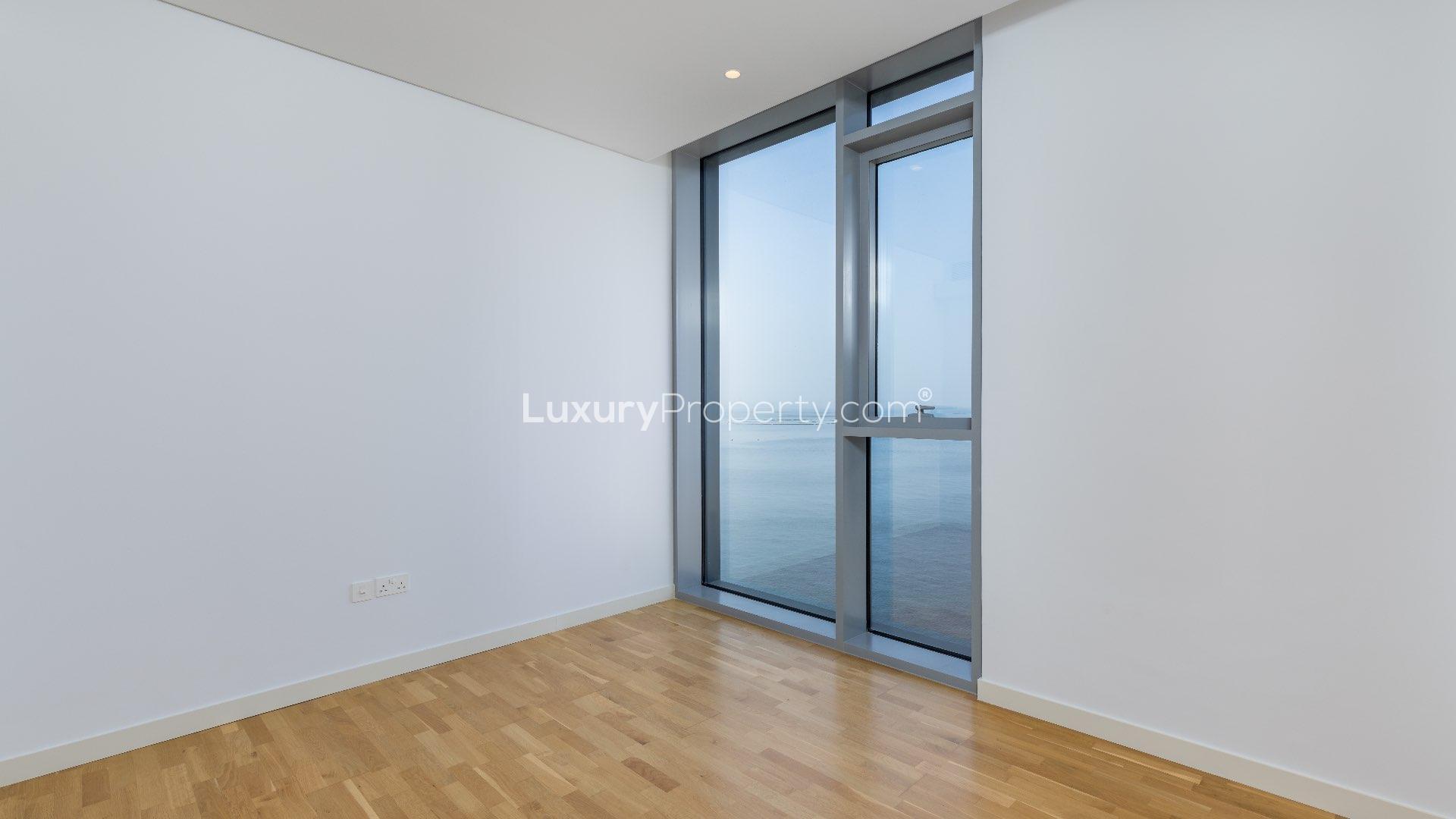 Empty room with large window, hardwood floor in Bluewaters Residences apartment for rent