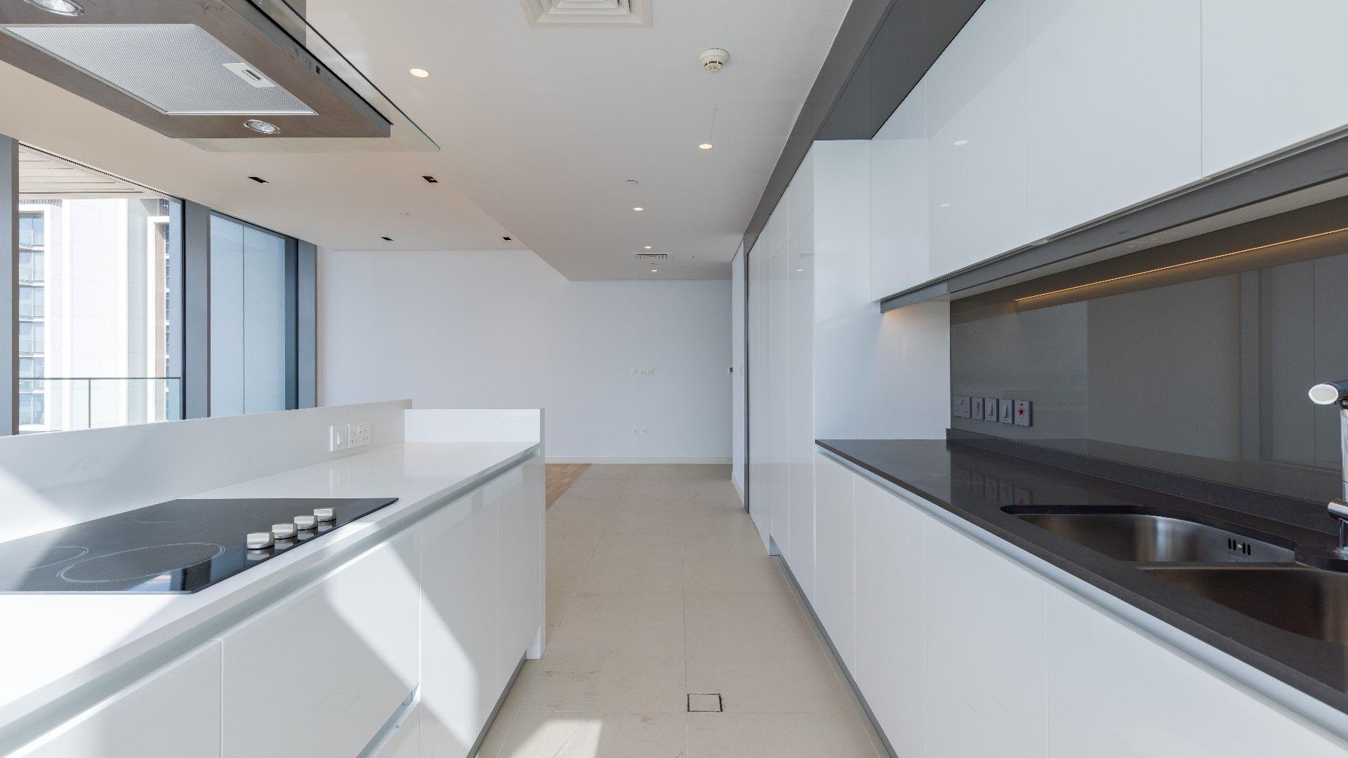 Modern kitchen in three-bedroom Bluewaters apartment for rent, featuring sleek white cabinetry