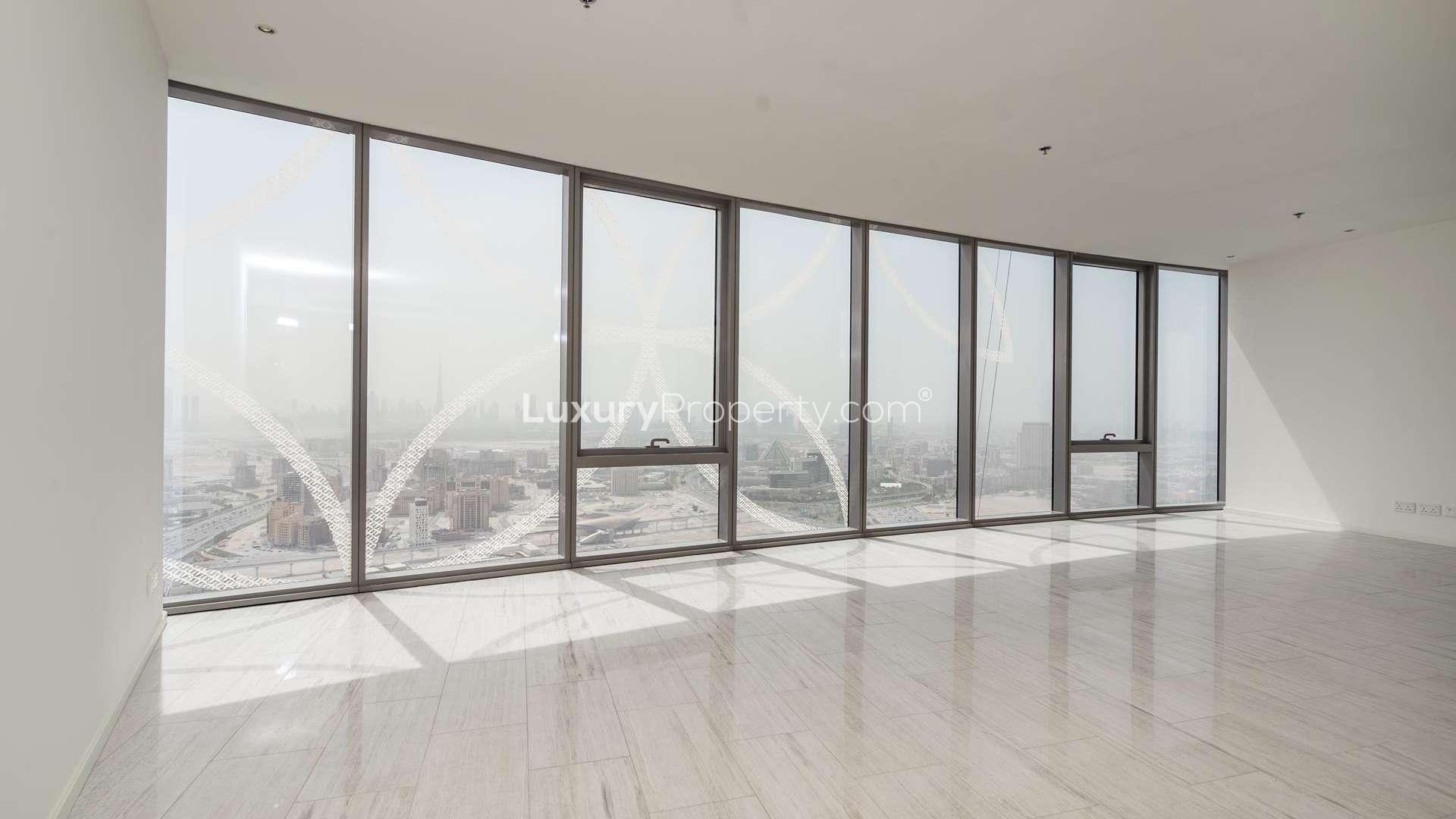 Empty room with large windows, hardwood floors, city view in D1 Tower, Dubai apartment
