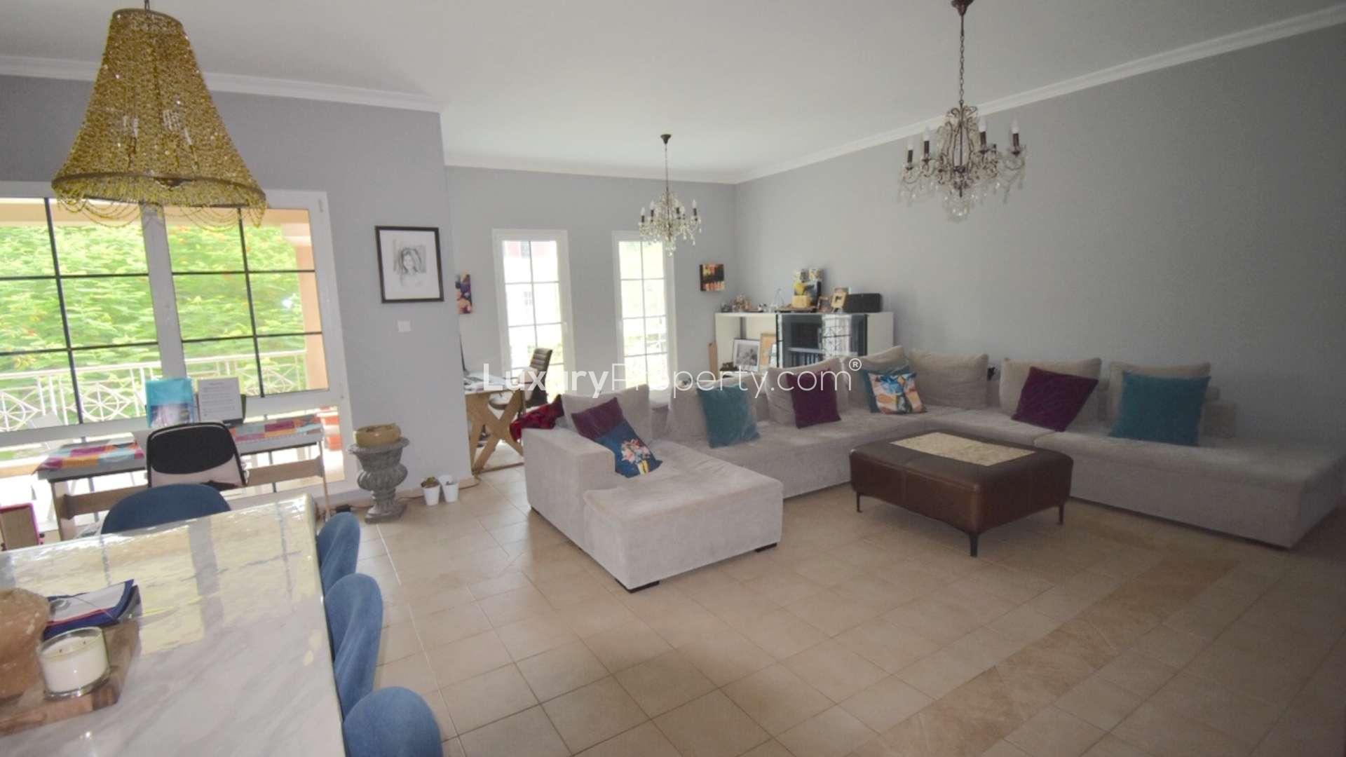 Three-bed apartment balcony view of lush garden and palm trees in Green Community