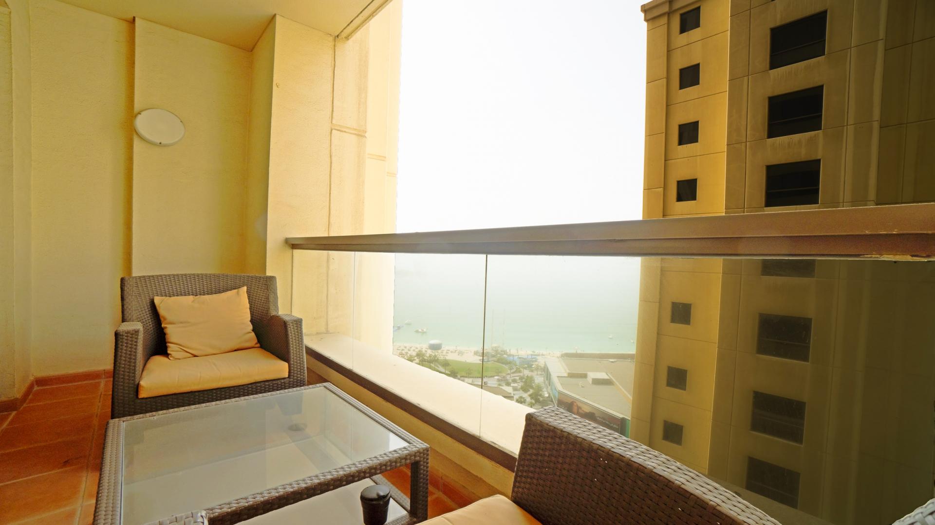 Dining area in spacious JBR apartment with modern decor and balcony access