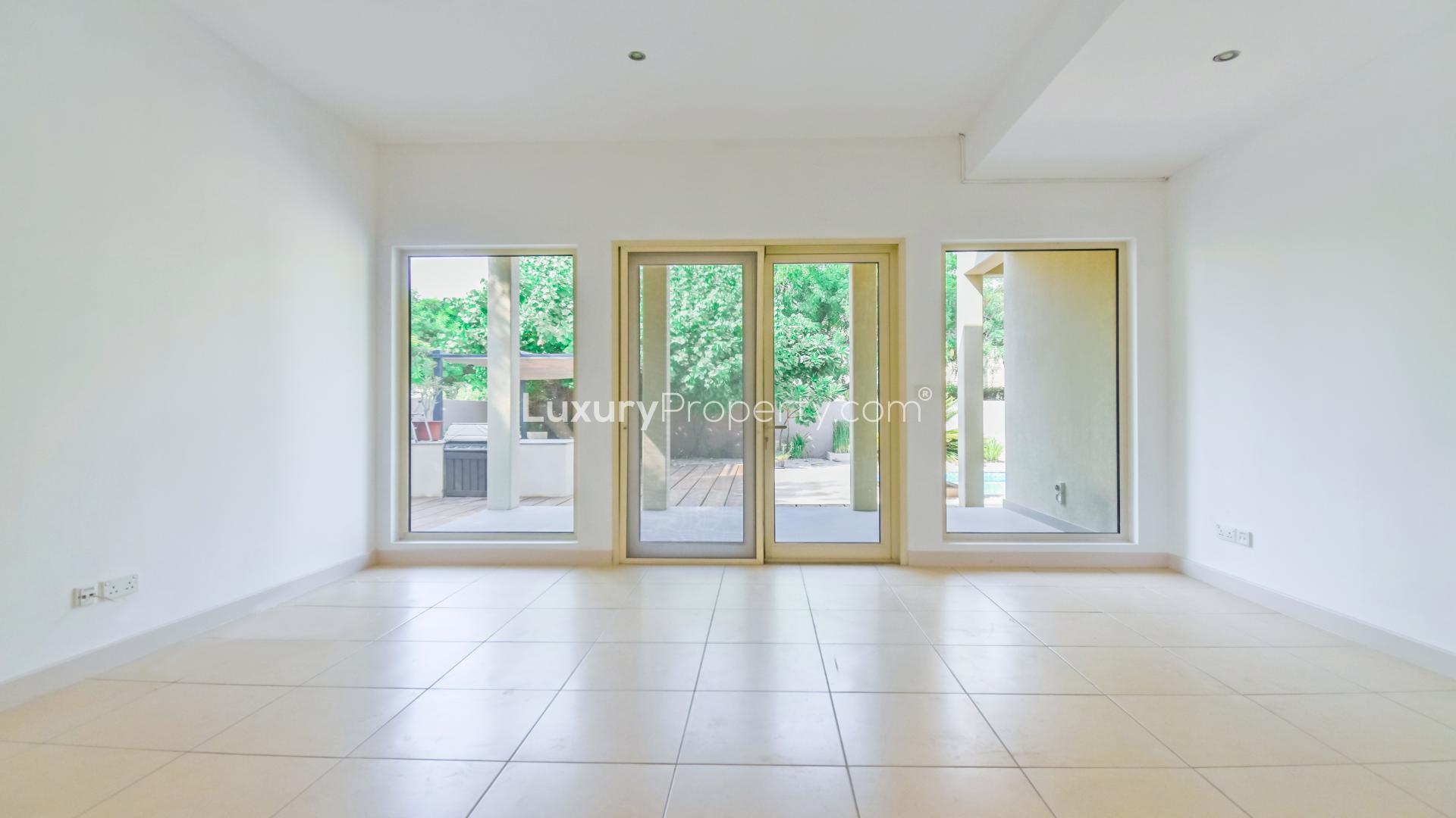 Bright living room with large windows overlooking private pool in Saheel villa, Arabian Ranches