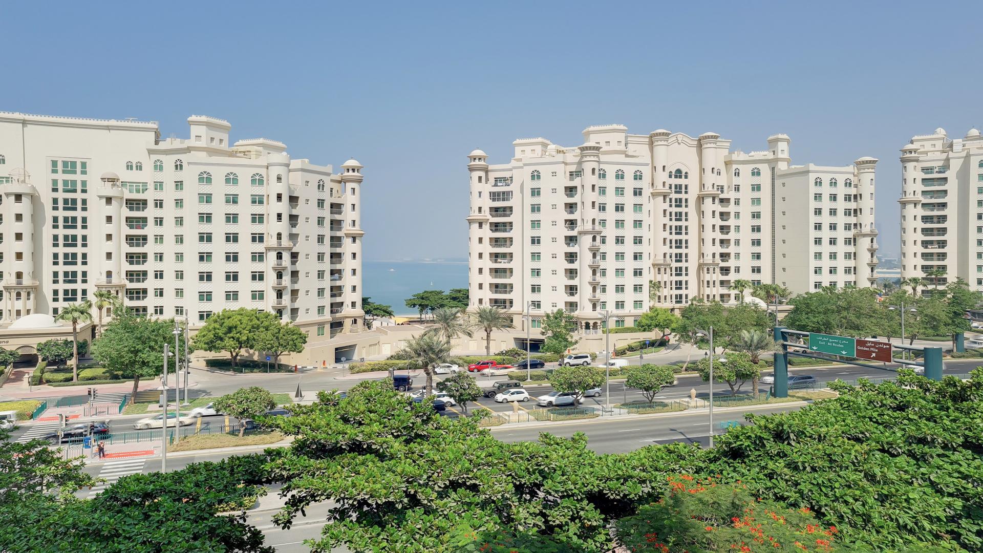 Mid-floor Shoreline Apartments, Palm Jumeirah, exterior view with lush landscaping and parked cars
