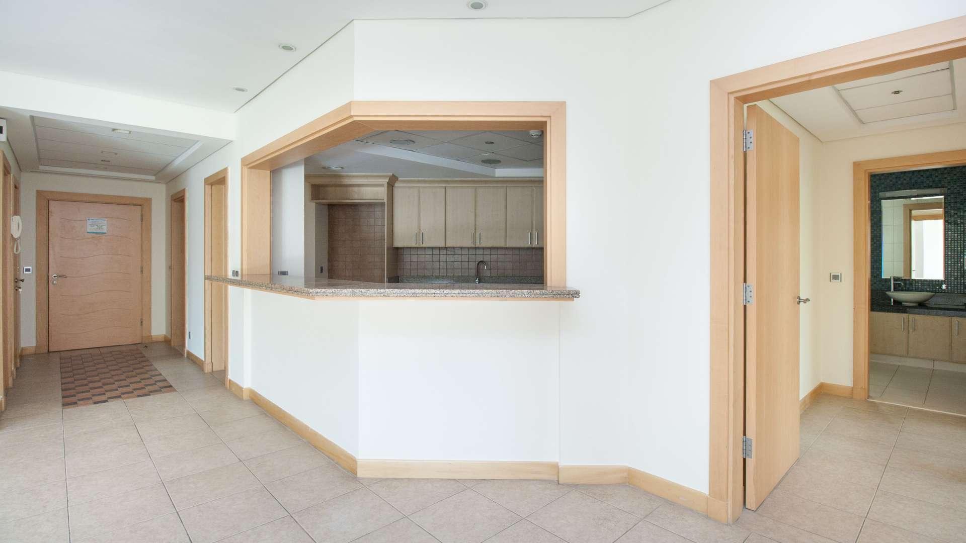 "Spacious Palm Jumeirah apartment interior with kitchen view, Shoreline Apartments, for sale.",Spacious living area in three-bed apartment, Shoreline Apartments, Palm Jumeirah, with natural light