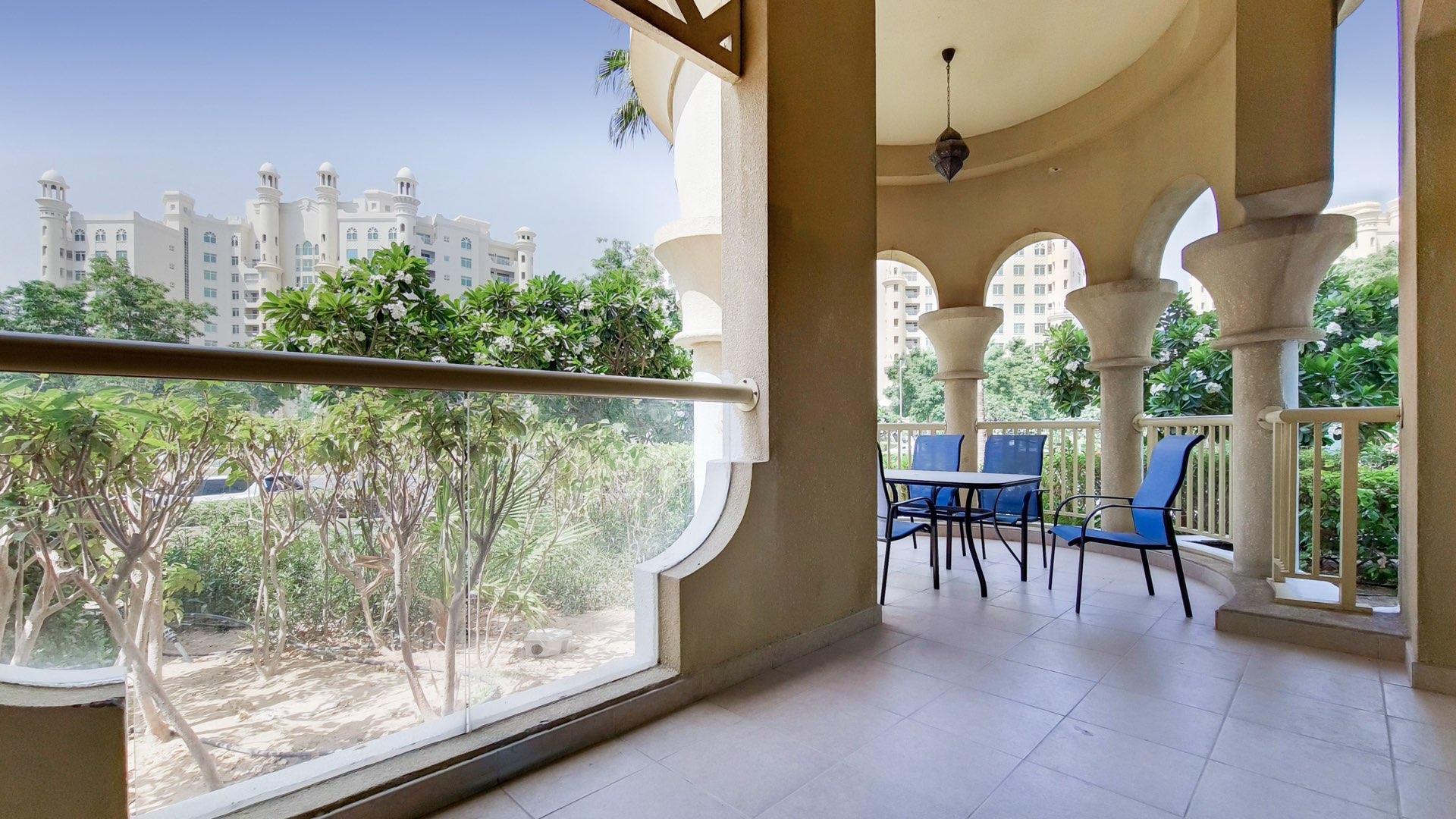"Bright bedroom in Palm Jumeirah apartment, featuring modern decor and large window view.",Spacious balcony view in Shoreline Apartments, Palm Jumeirah, Dubai, with lush greenery and seating