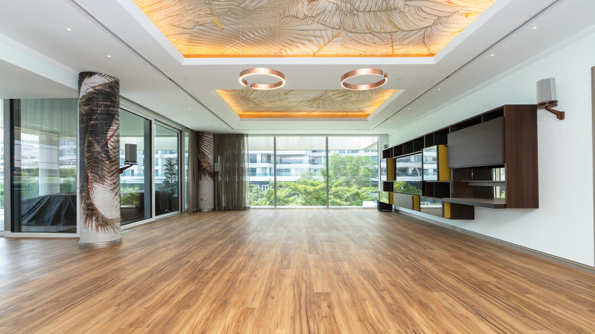 Modern open-plan living area with large windows in Al Barari's Ashjar apartment