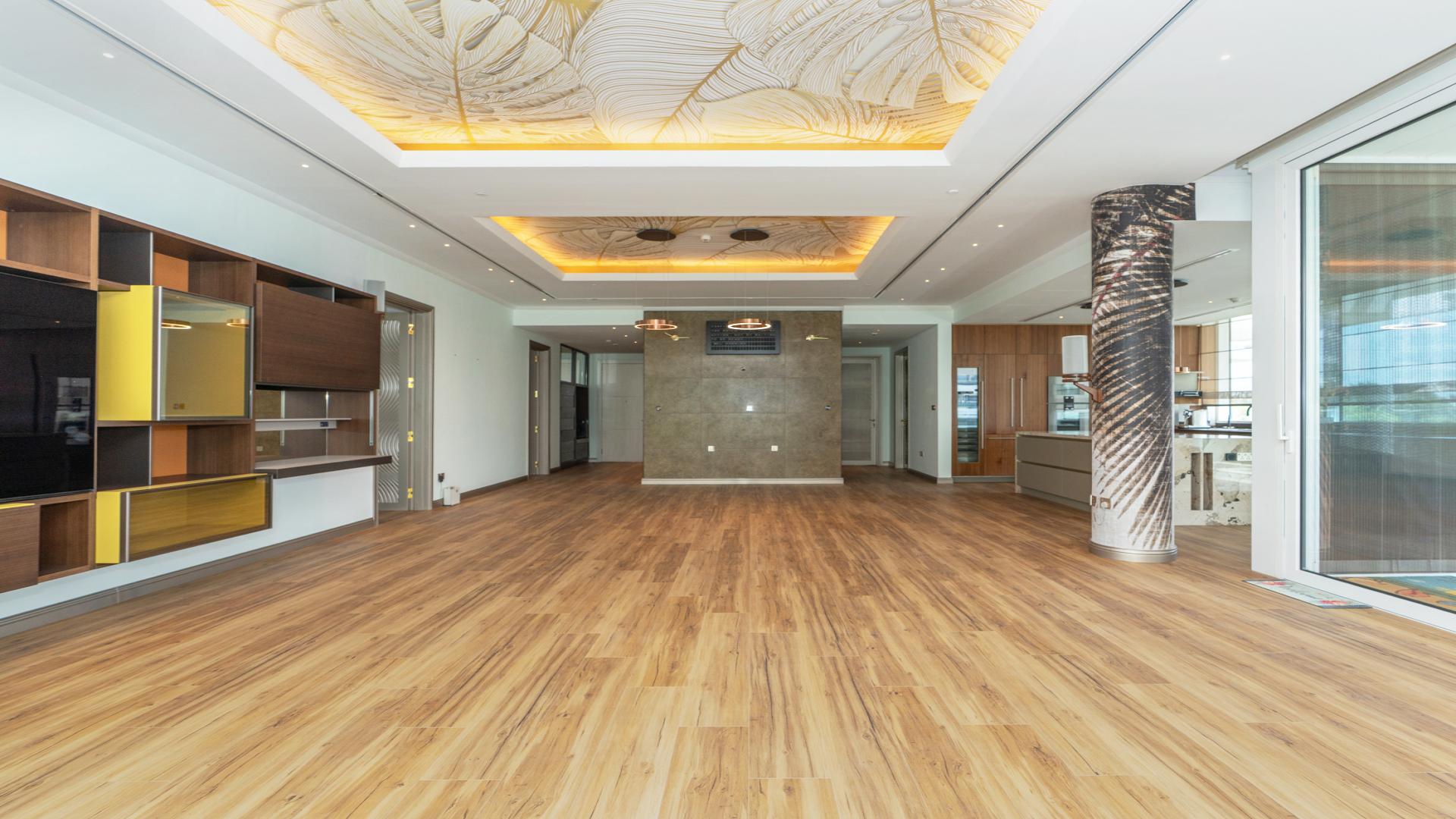 Spacious modern living room with wooden floors and large windows in Al Barari apartment