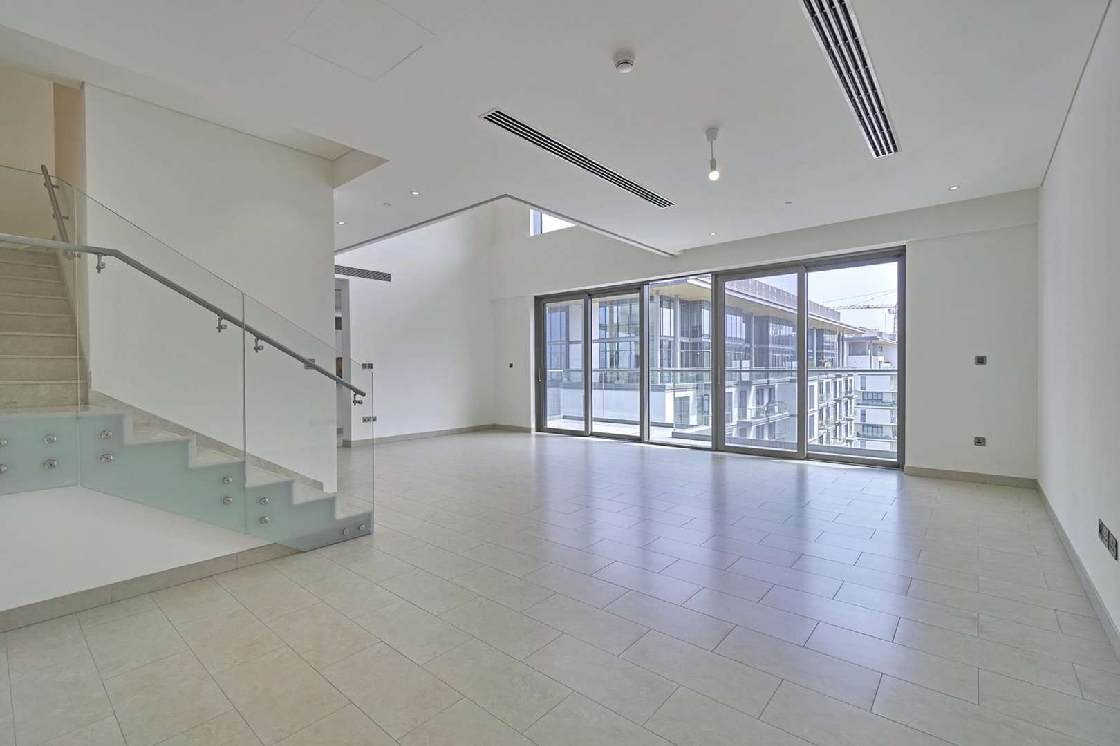 "Spacious balcony view in Hartland Greens duplex, Sobha Hartland, Mohammed Bin Rashid City.",Spacious living area in three-bedroom duplex, Sobha Hartland, with large windows and staircase