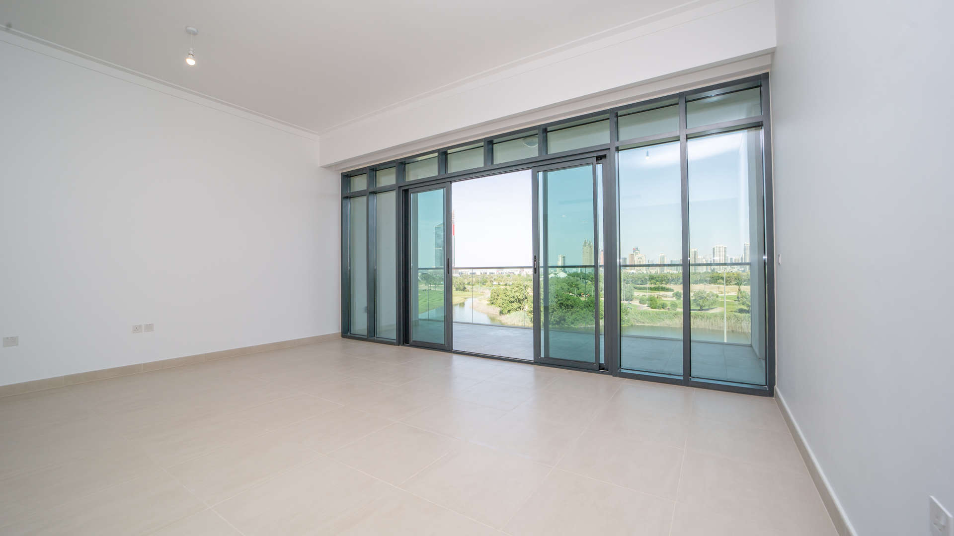 Empty room with large windows overlooking Emirates Golf Course, The Hills A, Dubai apartment