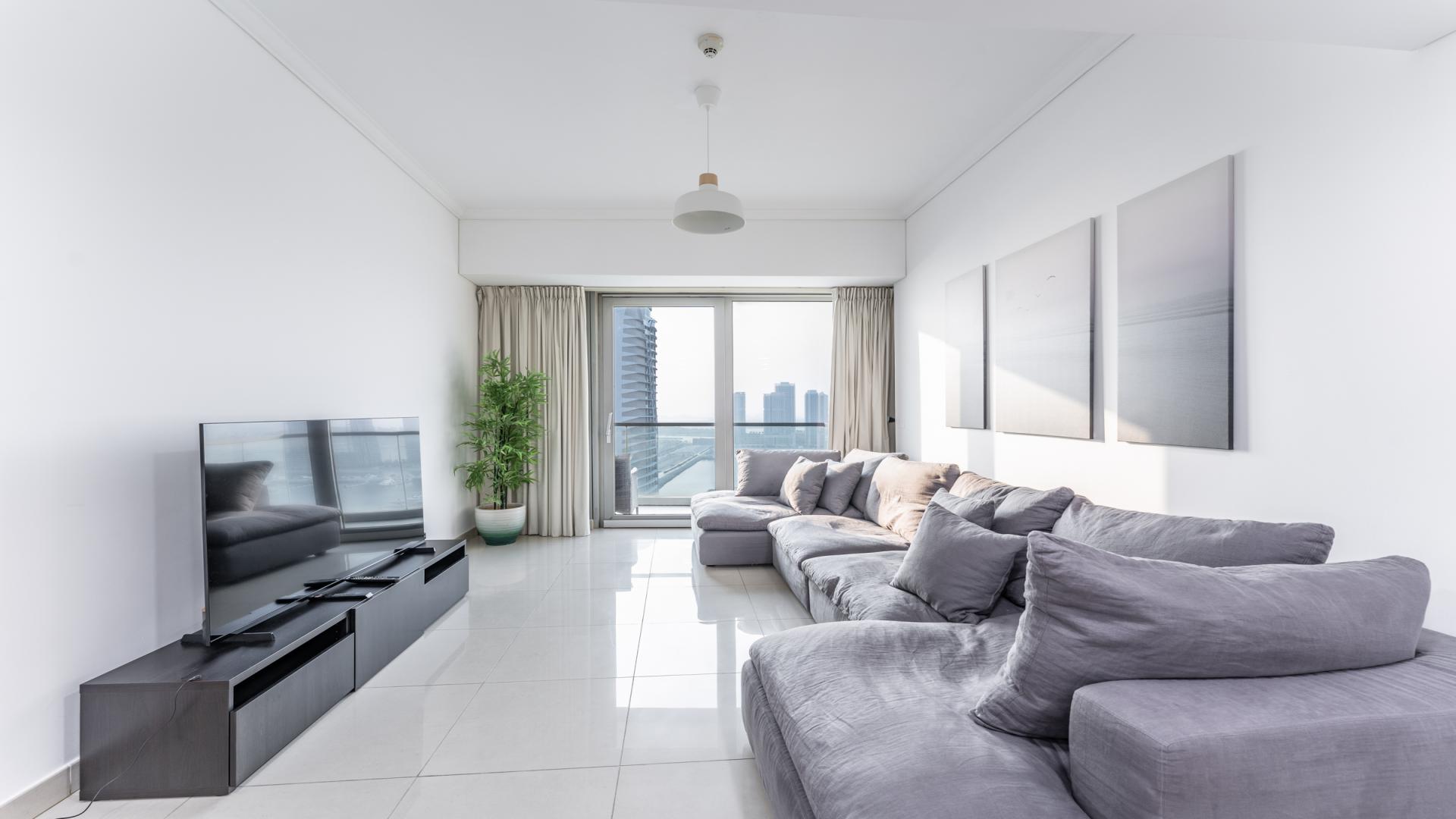 "Stunning Dubai Marina view from Ocean Heights apartment balcony, showcasing waterfront skyline and cityscape.",Modern living room in Ocean Heights apartment, featuring large sofa and city views