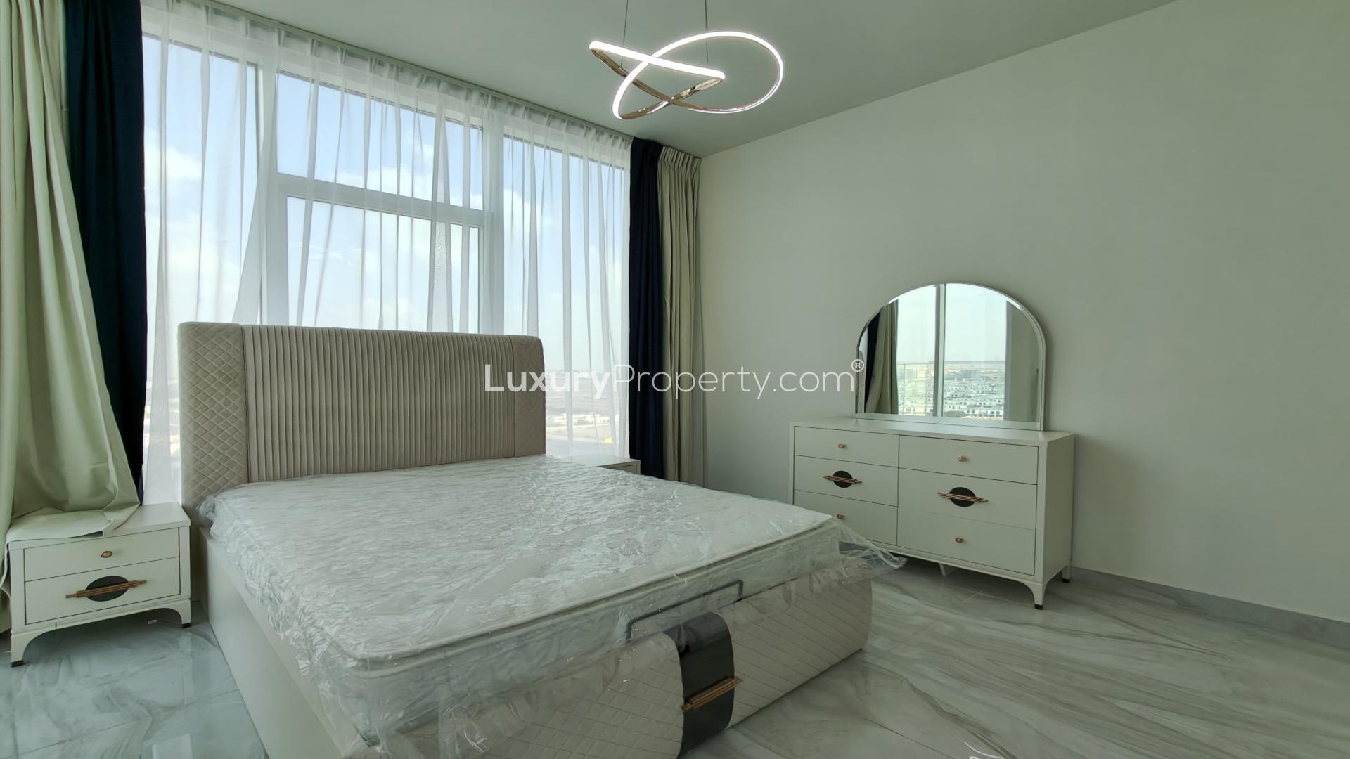 Modern bedroom in Al Furjan penthouse, featuring elegant bed and dresser with city view
