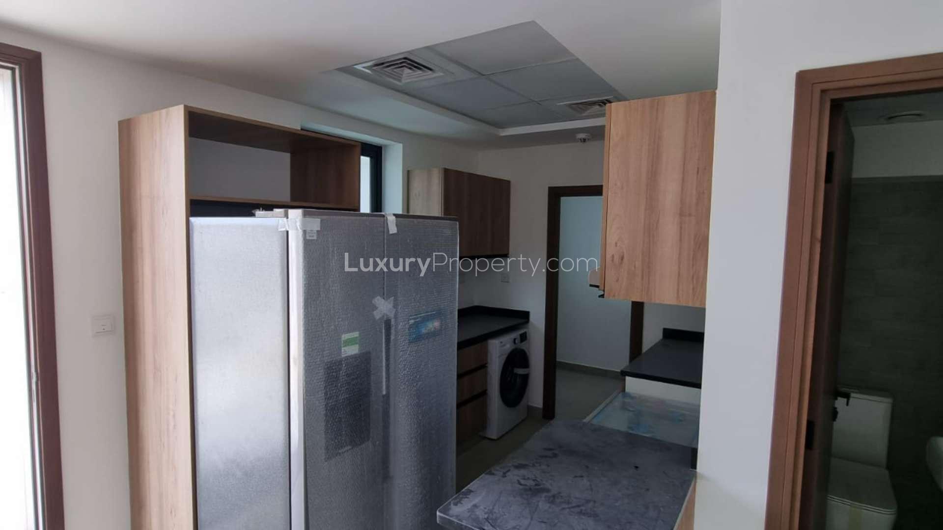 Modern kitchen in 3-bedroom townhouse, Rukan 2, Dubai Land, with appliances and wooden cabinets