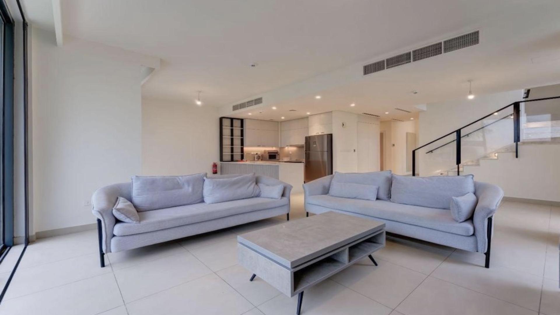 Modern living room in Dubai Hills townhouse with garden view and large windows