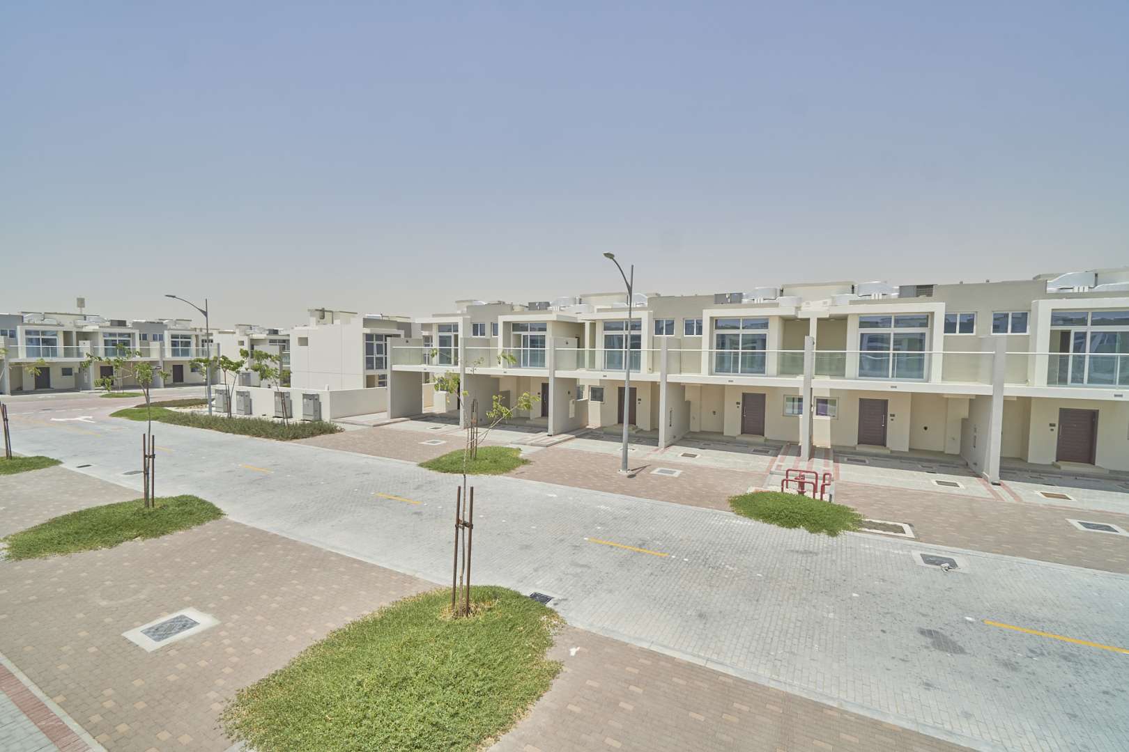 Three-bedroom townhouse patio in Albizia, Damac Hills 2, with large windows and sandy yard