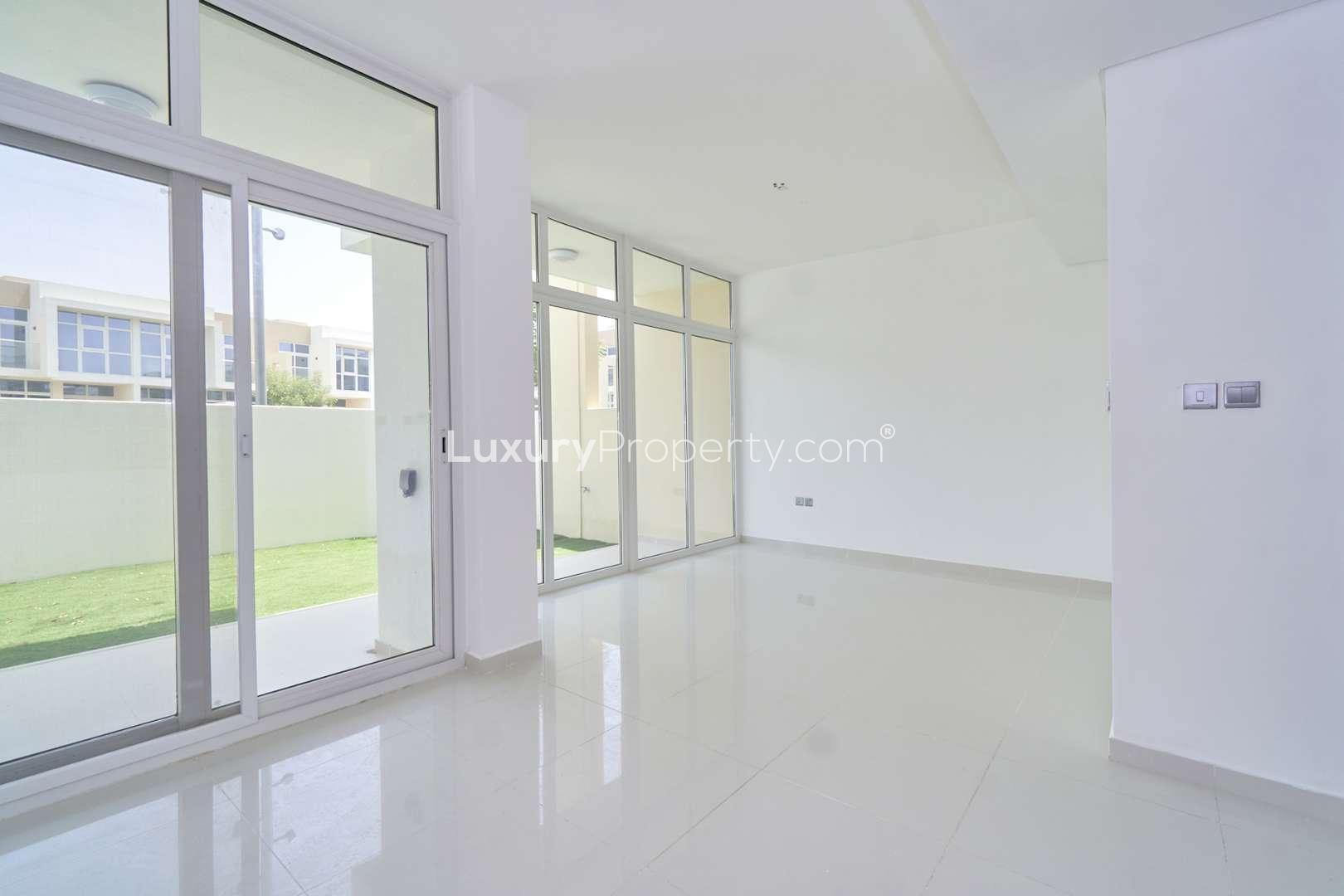 Outdoor view of townhouses in Amazonia, Damac Hills 2, with green lawn and play area