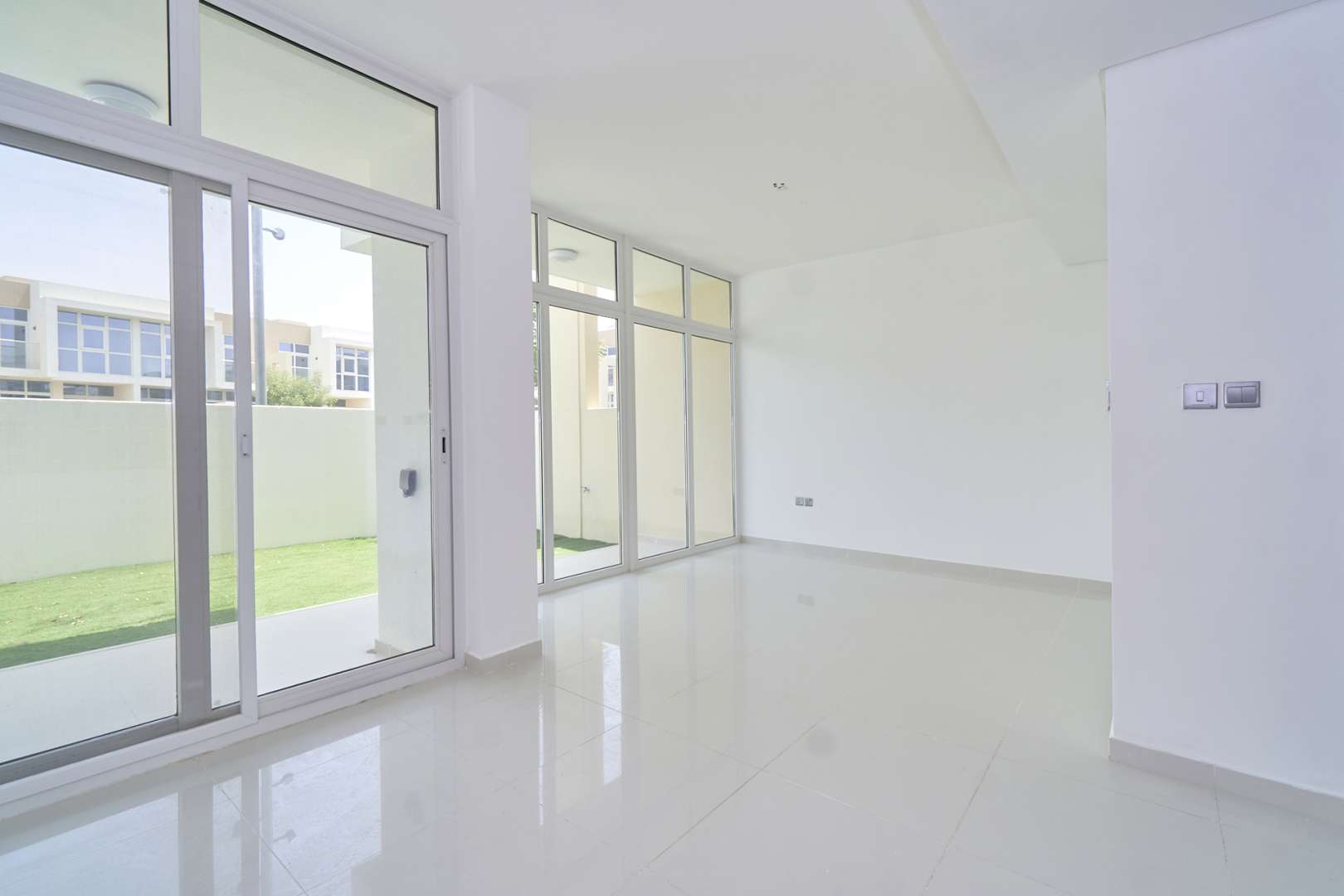 Outdoor view of townhouses in Amazonia, Damac Hills 2, with green lawn and play area