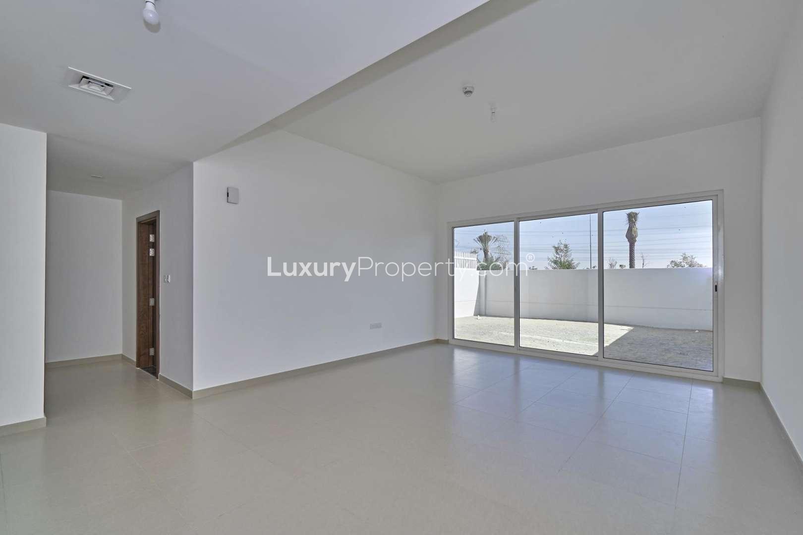 Empty living room with large sliding glass doors in Arabella Townhouse, Mudon community