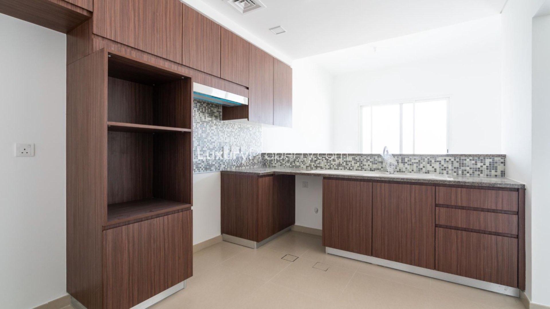 Modern kitchen with wooden cabinetry in Arabella Townhouses, Mudon. Type B layout townhouse