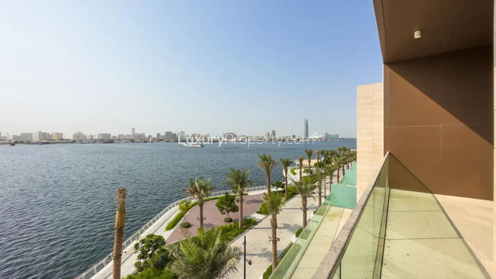 "Stunning waterfront view from townhouse balcony in The Grand, Dubai Creek Harbour.",Modern kitchen with large windows and waterfront view in Dubai Creek Harbour townhouse