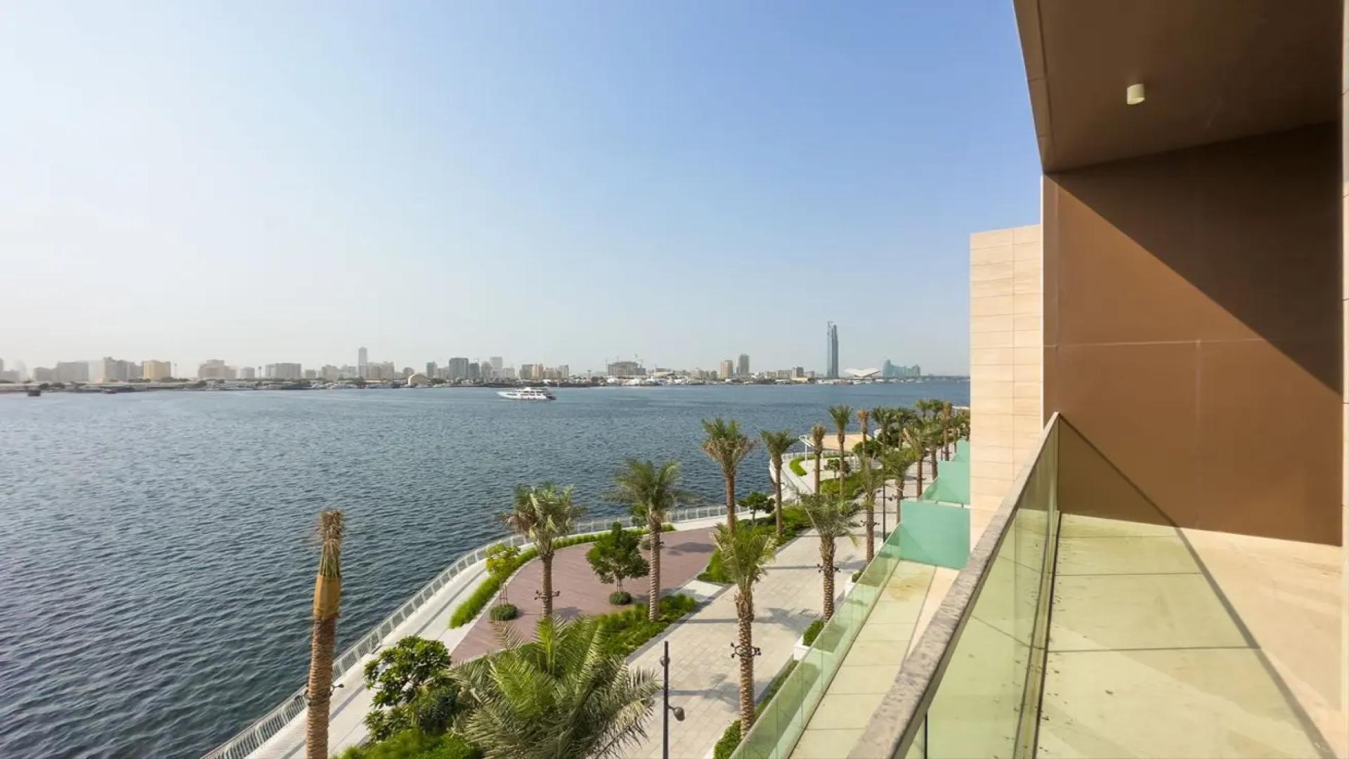 "Stunning waterfront view from townhouse balcony in The Grand, Dubai Creek Harbour.",Modern kitchen with large windows and waterfront view in Dubai Creek Harbour townhouse